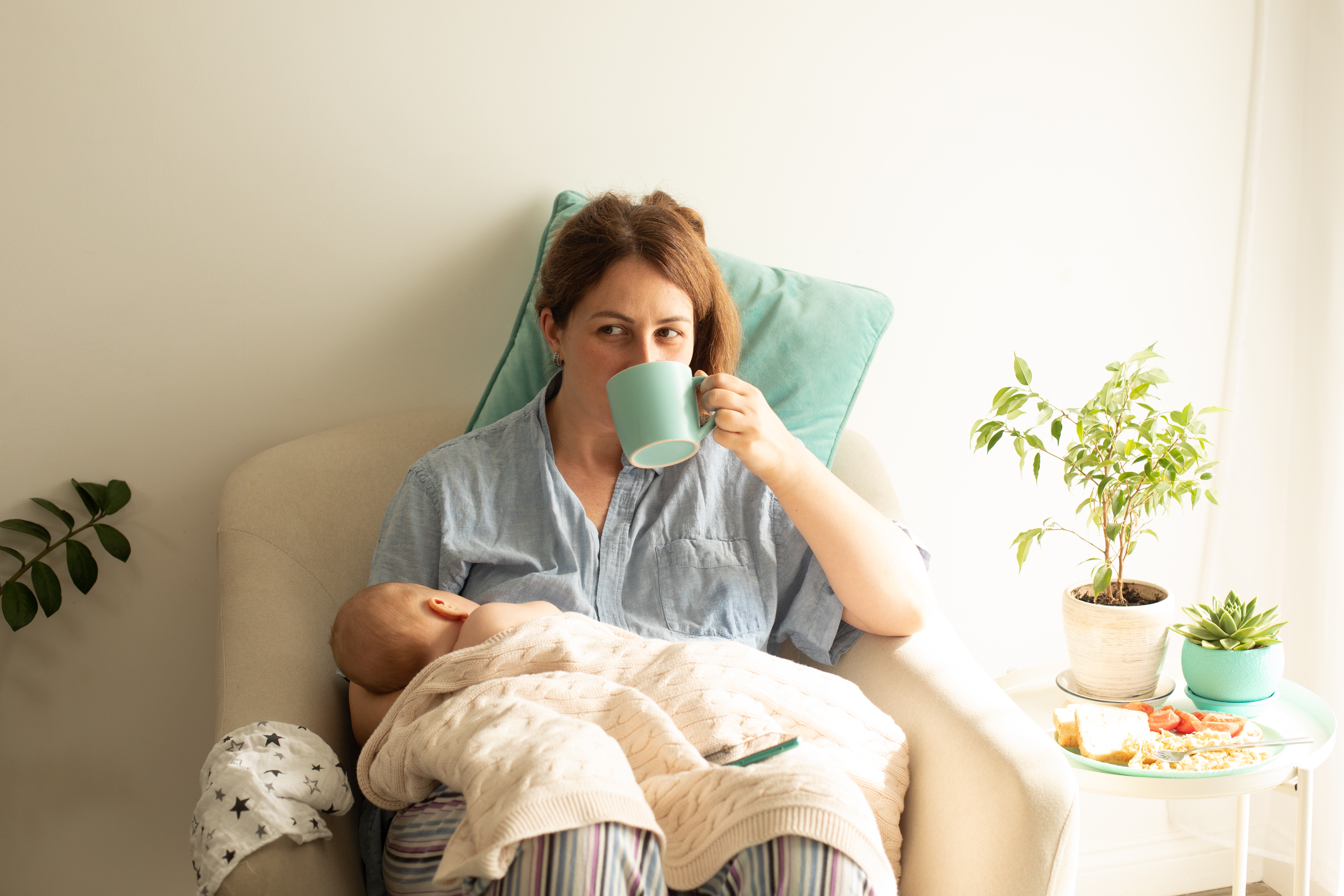 Une femme qui boit du thé en tenant son bébé | Source : Shutterstock