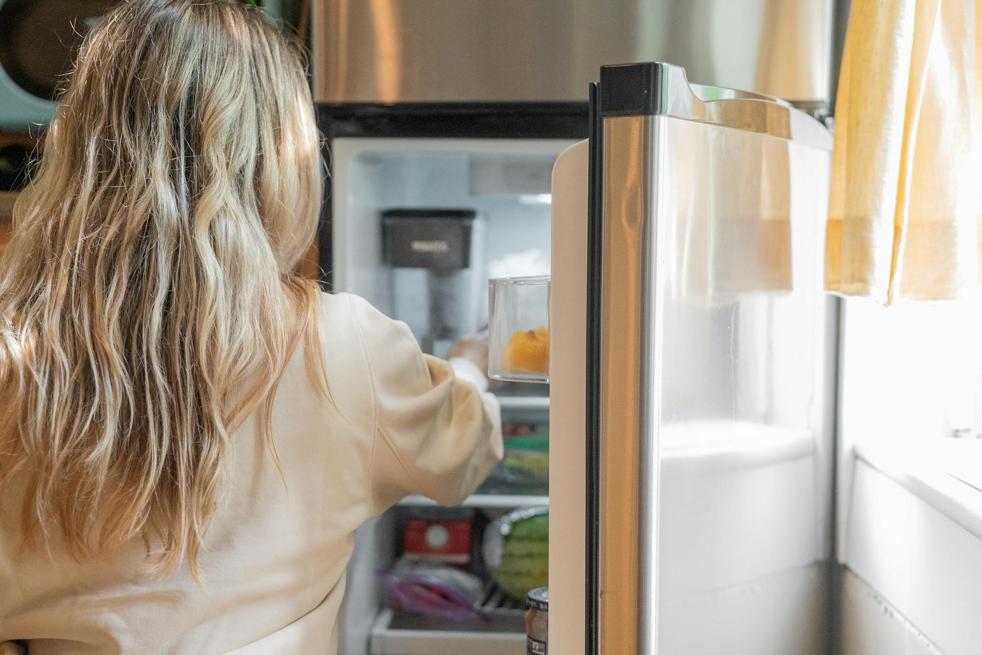 Une femme plongeant la main dans un réfrigérateur | Source : Pexels