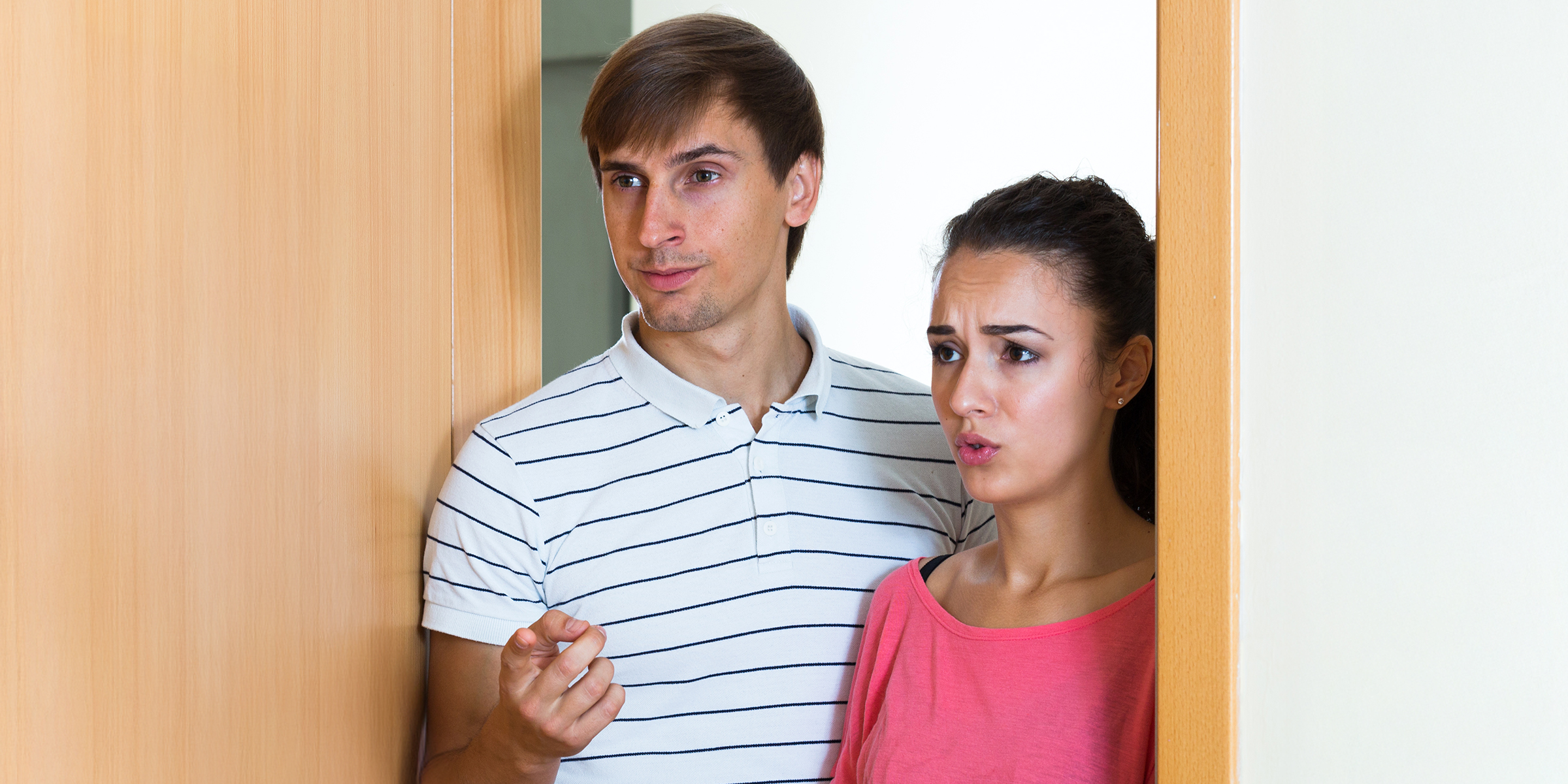 Un couple anxieux se tenant devant une porte | Source : Shutterstock