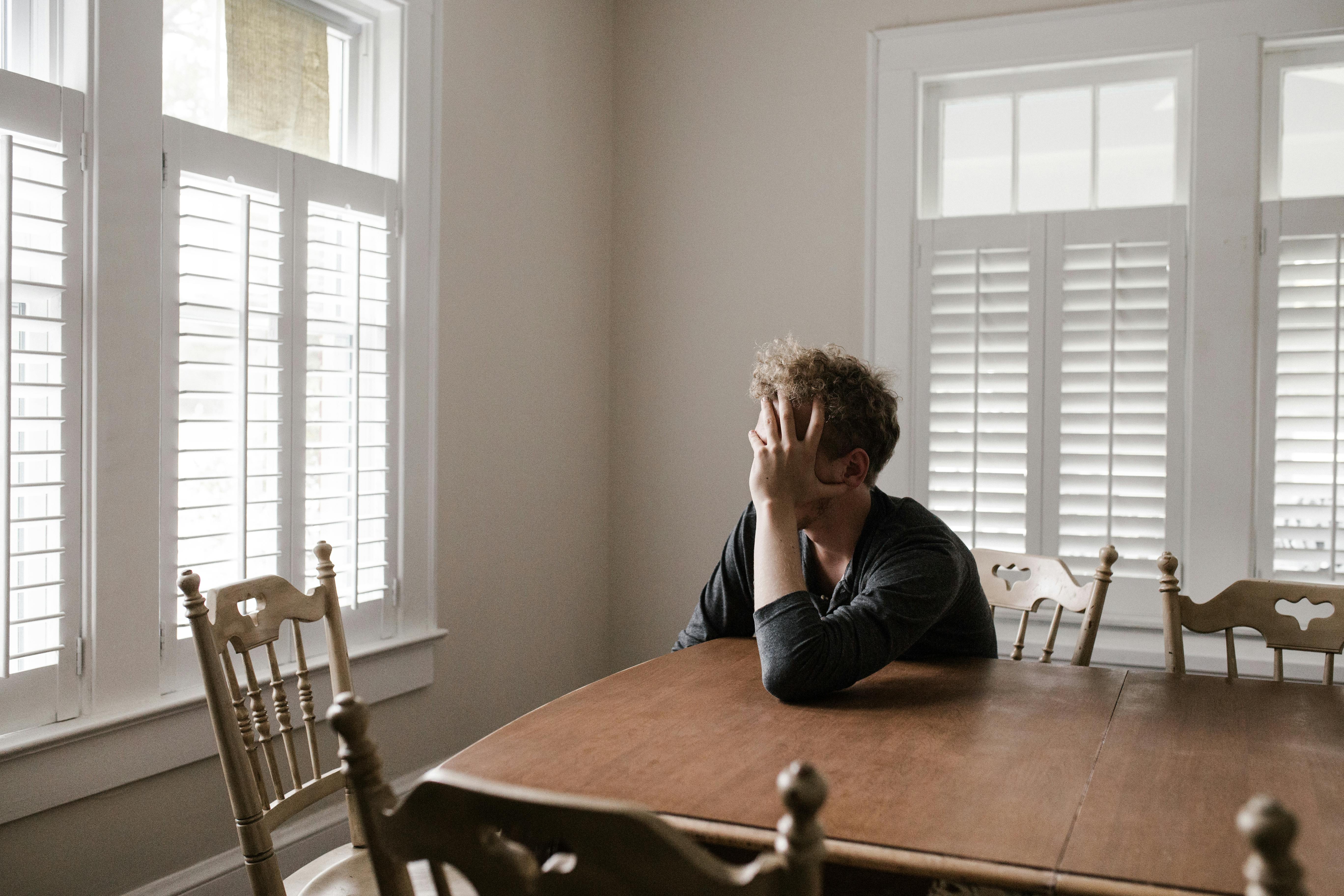 Un homme contrarié assis à une table | Source : Pexels