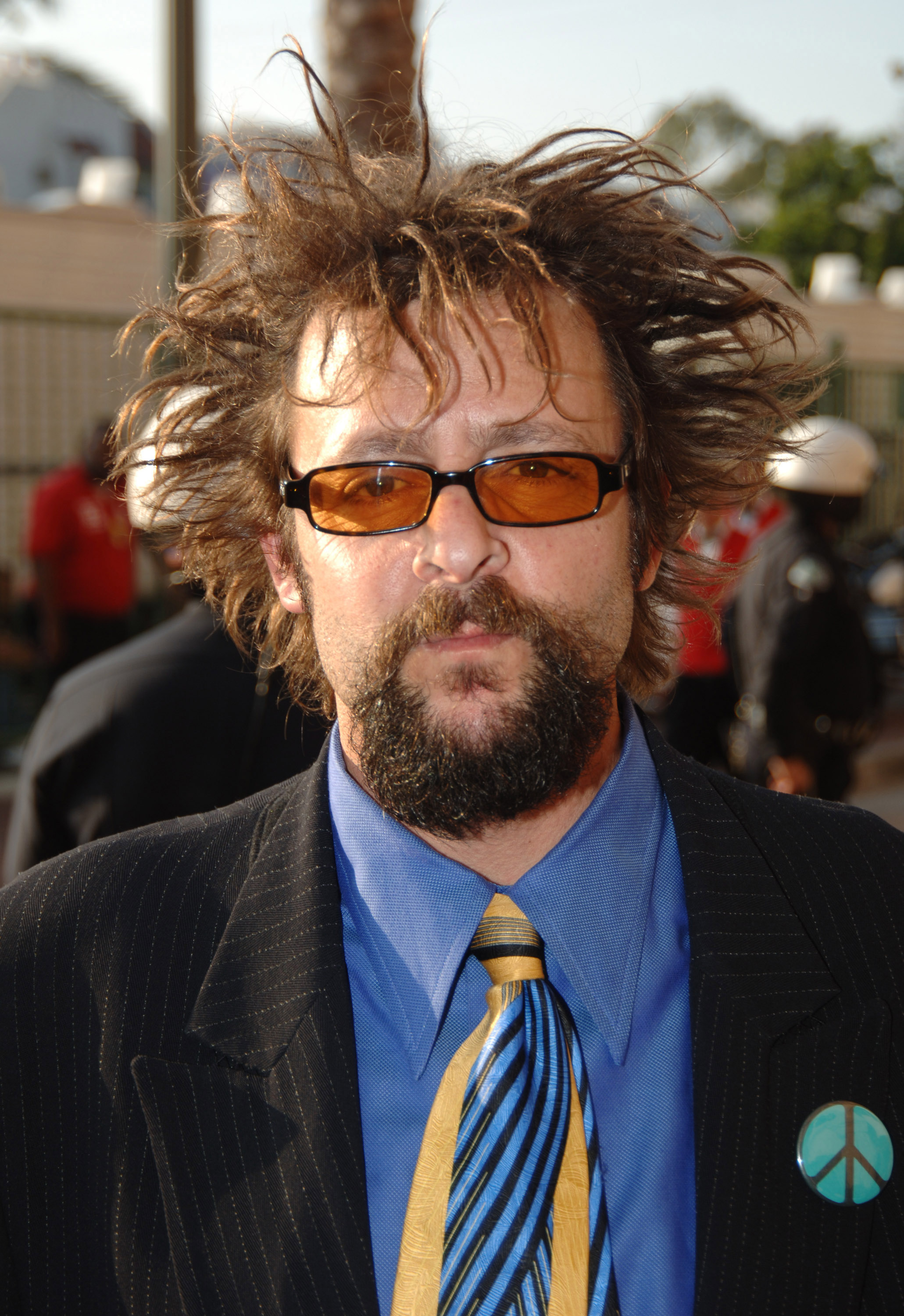 Avec sa coiffure hérissée caractéristique, ses lunettes de soleil teintées d'orange et un pin's en forme de signe de paix sur sa veste de costume, la star a affiché un look audacieux sur le tapis rouge des MTV Movie Awards 2005 à Los Angeles. | Source : Getty Images