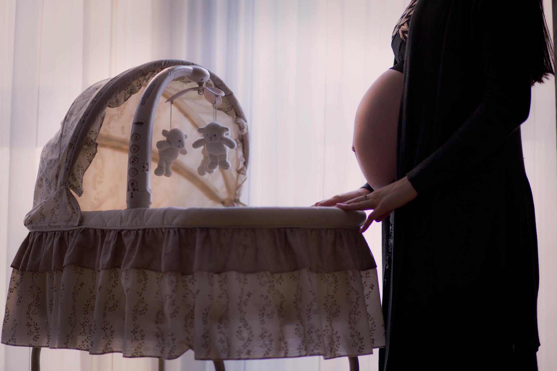 Une femme enceinte debout près d'un couffin | Source : Pexels