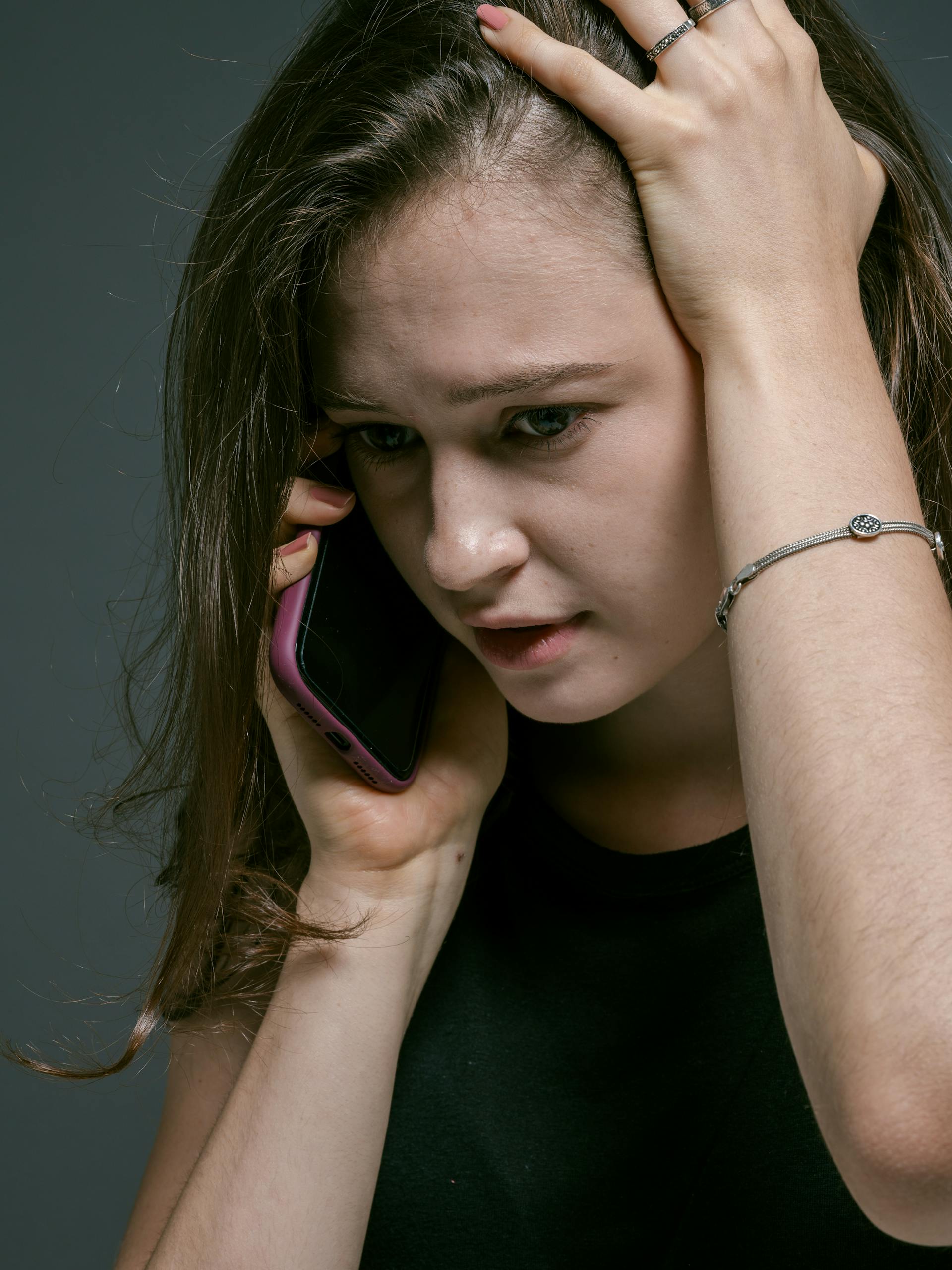 Une femme sur son téléphone portable, la main sur la tête | Source : Pexels