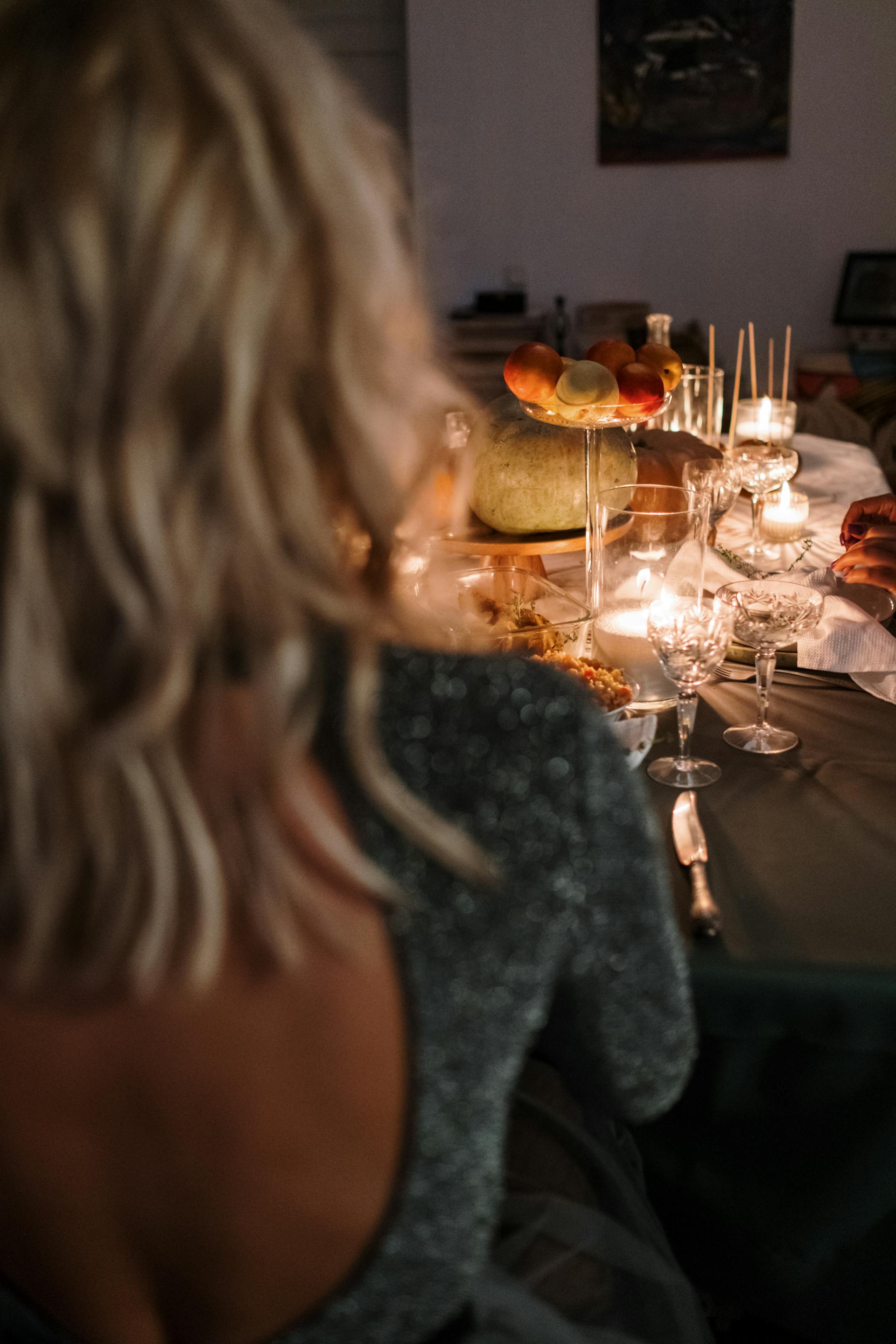 Une femme en robe dos nu assise à une table de dîner | Source : Pexels