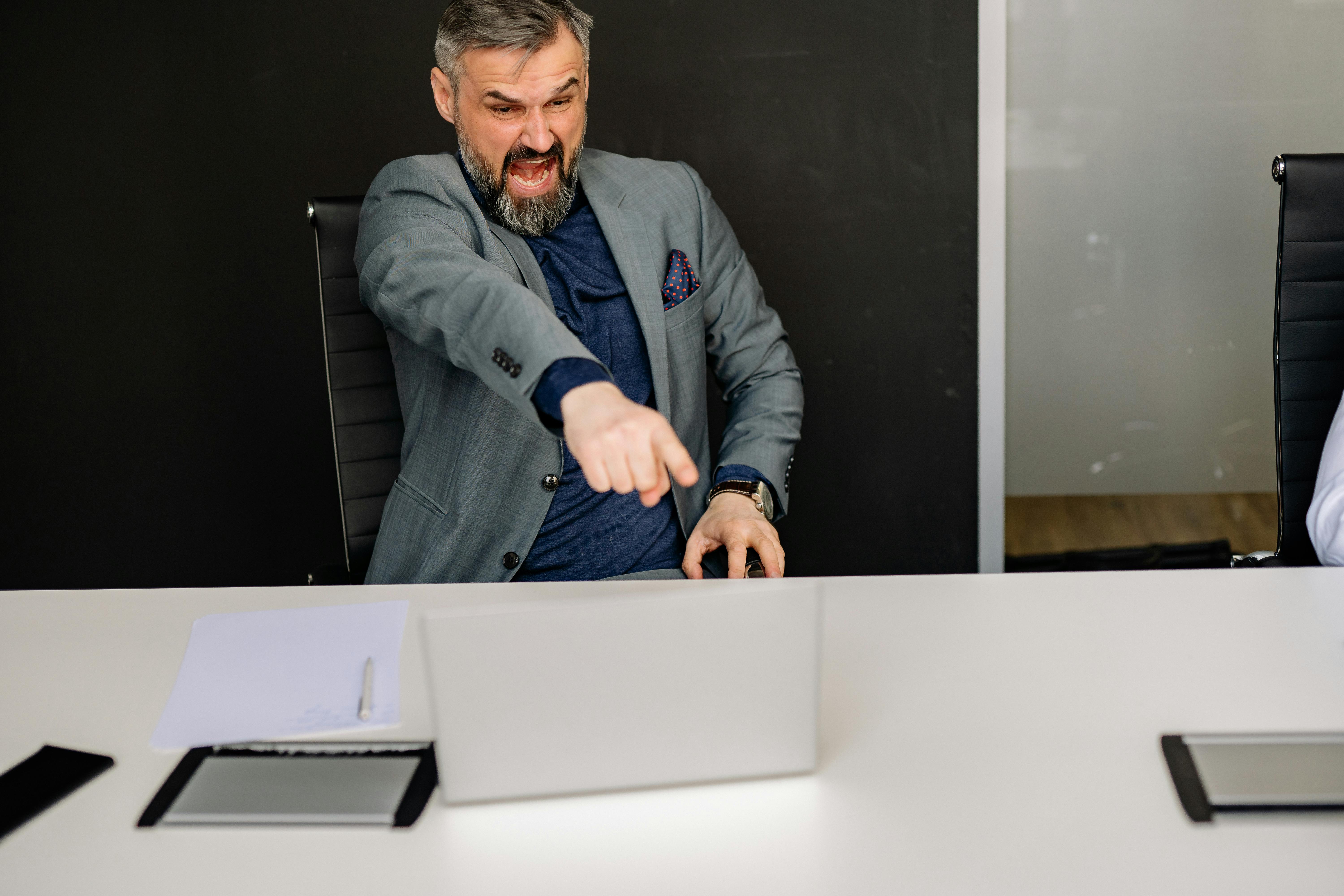Un homme d'affaires en colère pointant du doigt l'écran de son ordinateur portable | Source : Pexels