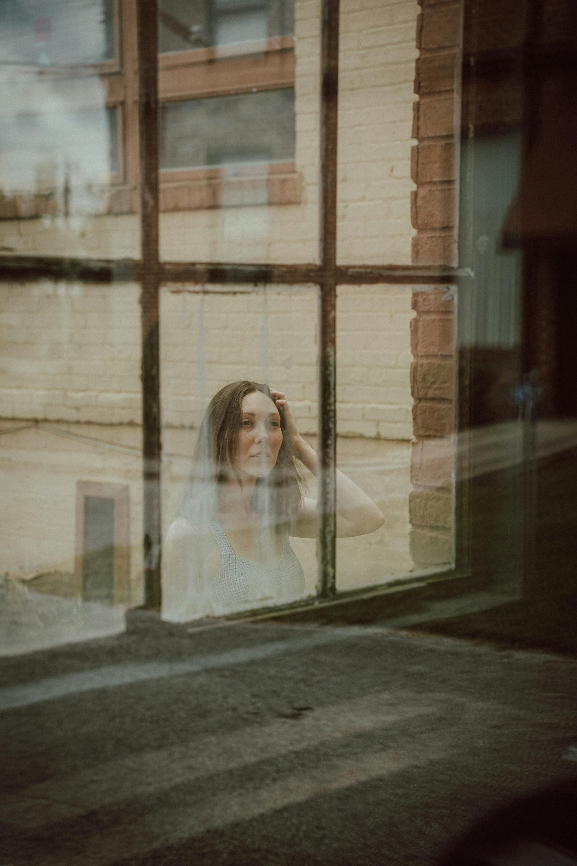 Une femme qui regarde à travers la fenêtre d'un bâtiment | Source : Pexels
