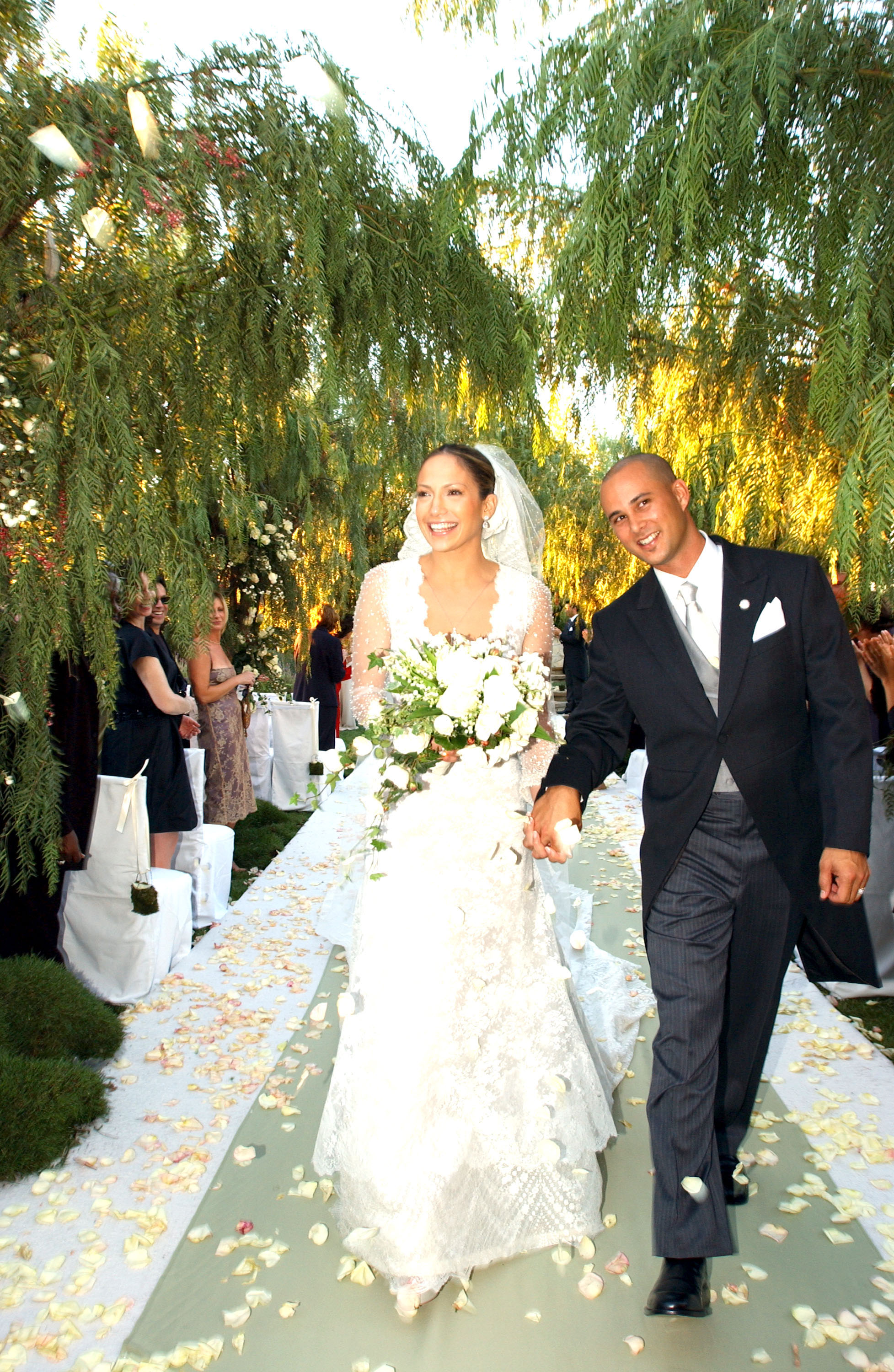 Jennifer Lopez et Cris Judd remontant l'allée le jour de leur mariage, le 29 septembre 2001. Entourés d'une végétation luxuriante et de pétales de roses blanches, le couple a célébré son union lors d'une magnifique cérémonie en plein air avant de se séparer moins d'un an plus tard.