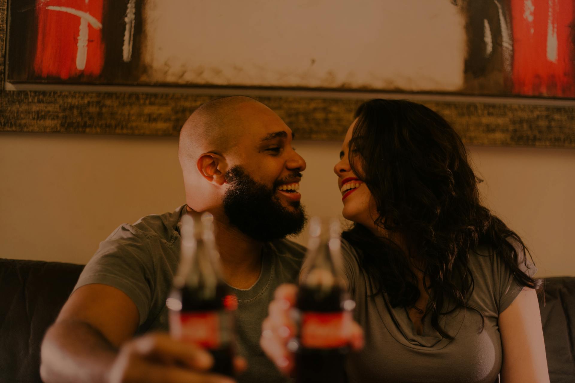 Un couple rit en tenant ses bouteilles de boissons gazeuses | Source : Pexels
