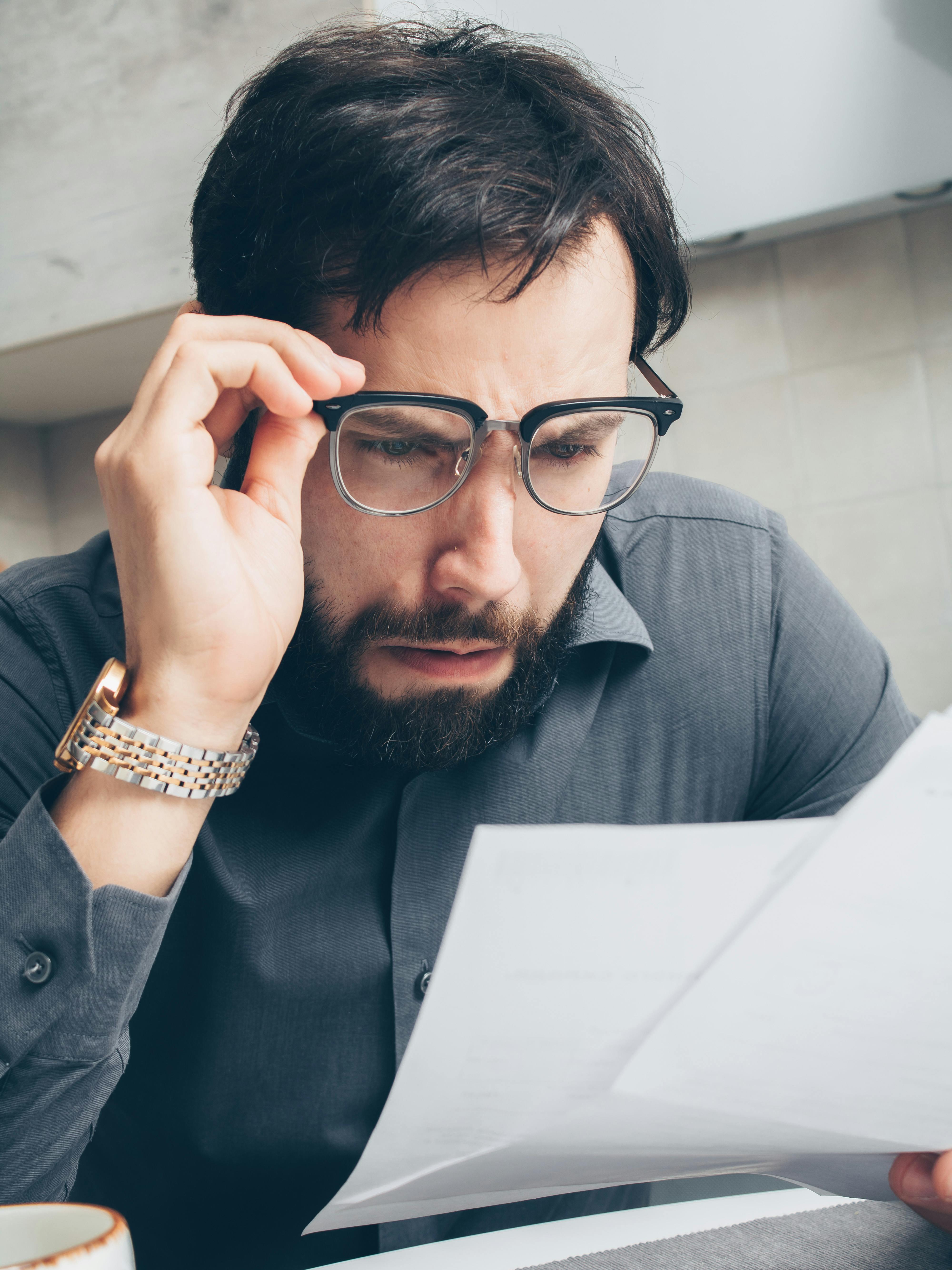 Homme choqué fixant un document | Source : Pexels