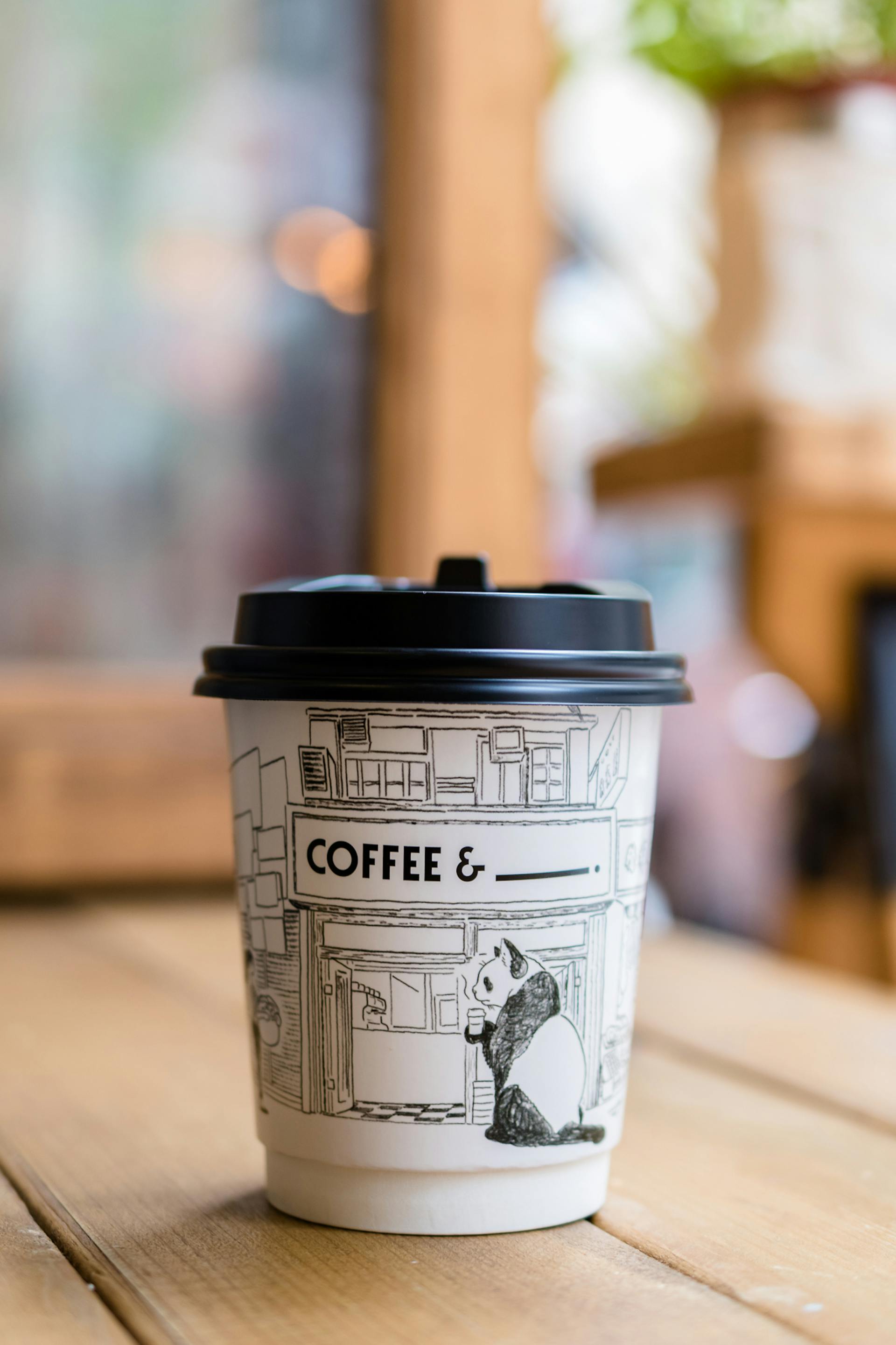 Café dans un gobelet en papier imprimé panda posé sur une table | Source : Pexels