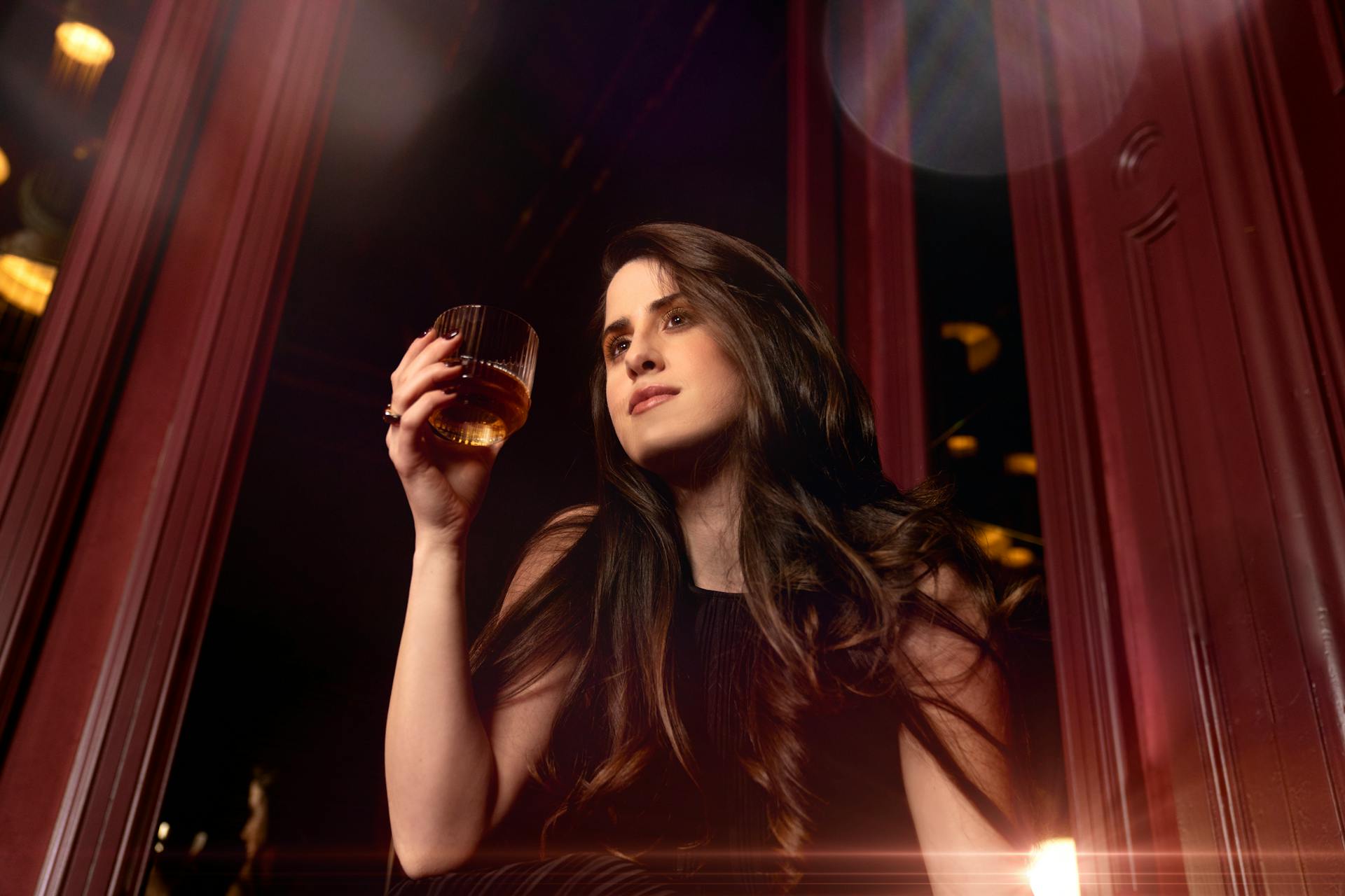 Plan en contre-plongée d'une femme tenant un verre de whisky | Source : Pexels