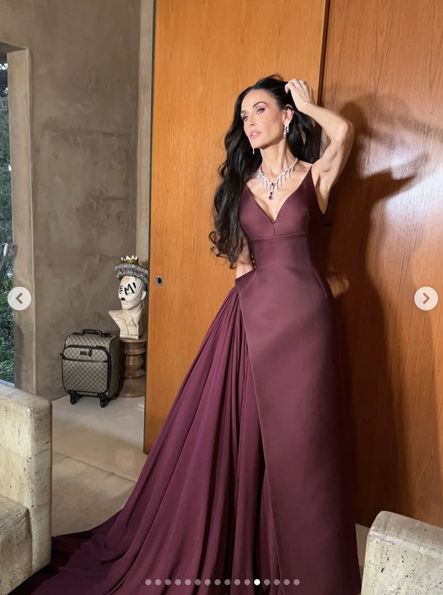Posant avec assurance devant un mur lambrissé, Demi Moore incarne le glamour de la haute couture dans sa robe bordeaux fluide, une main balayant ses cheveux en plein mouvement. | Source : Instagram/demimoore