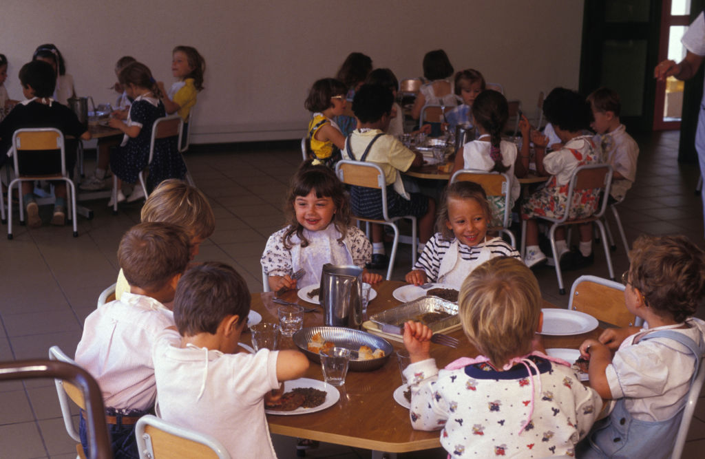 Enfants en train de déjeuner dans une salle | Source : Getty Images
