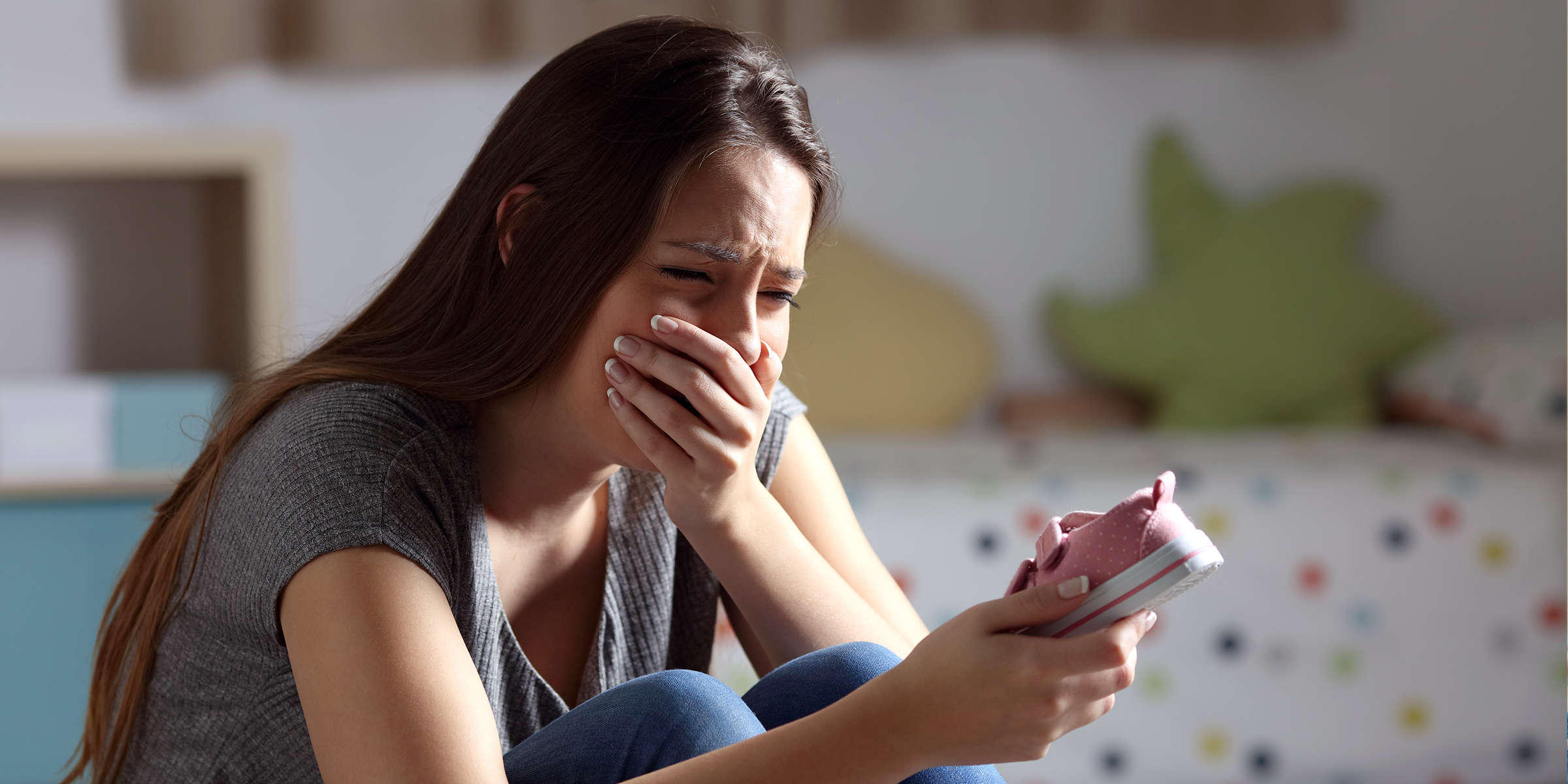 Femme qui pleure avec une petite chaussure dans la main | Source : Shutterstock