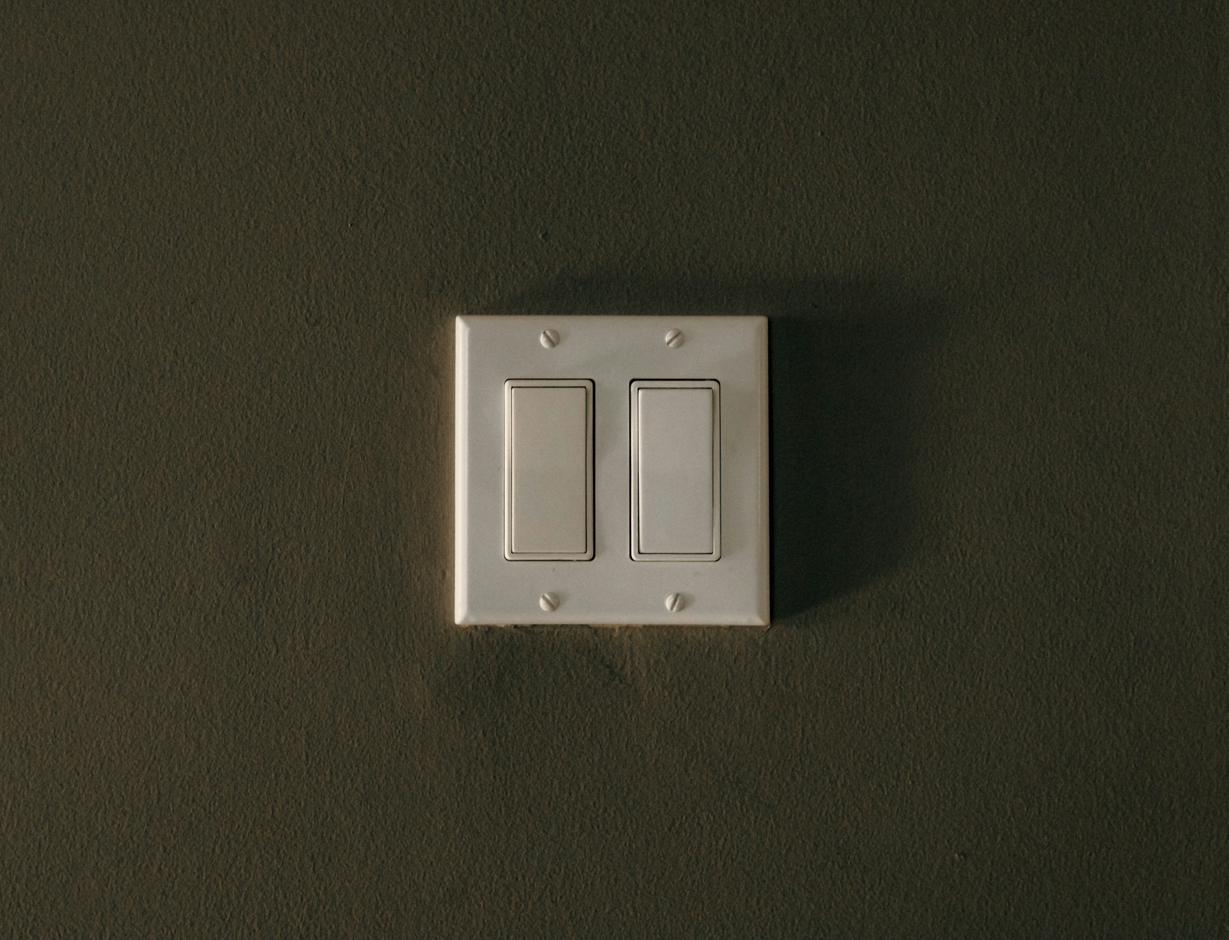 Double bouton d'interrupteur d'éclairage sur un mur | Source : Unsplash