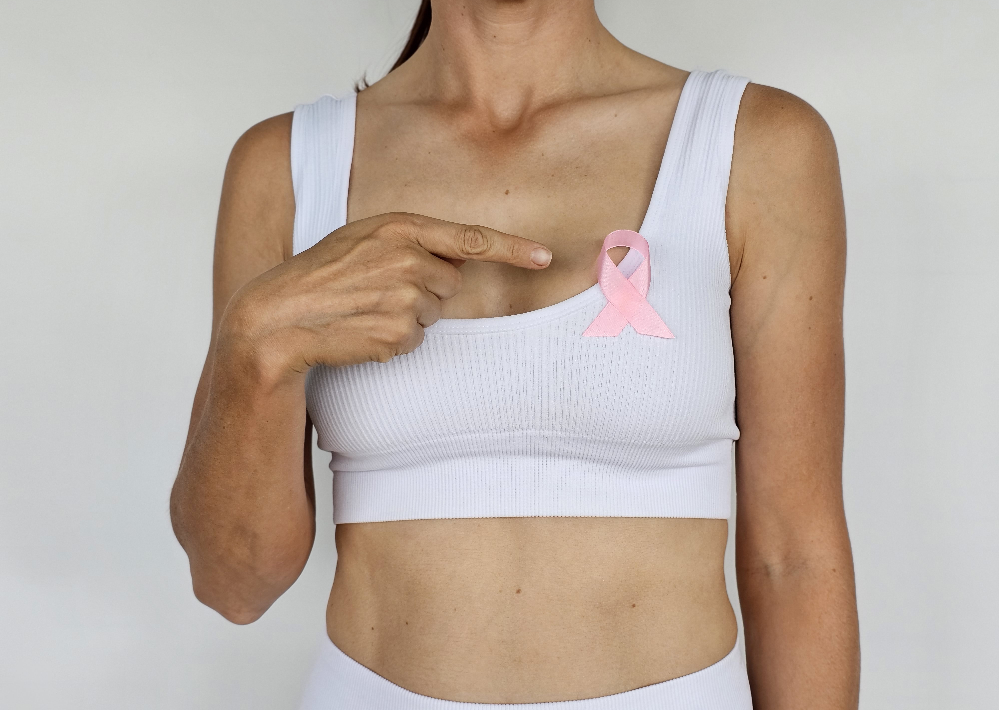 Une femme montre un ruban rose épinglé sur sa poitrine, symbolisant la sensibilisation au cancer du sein | Source : Getty Images