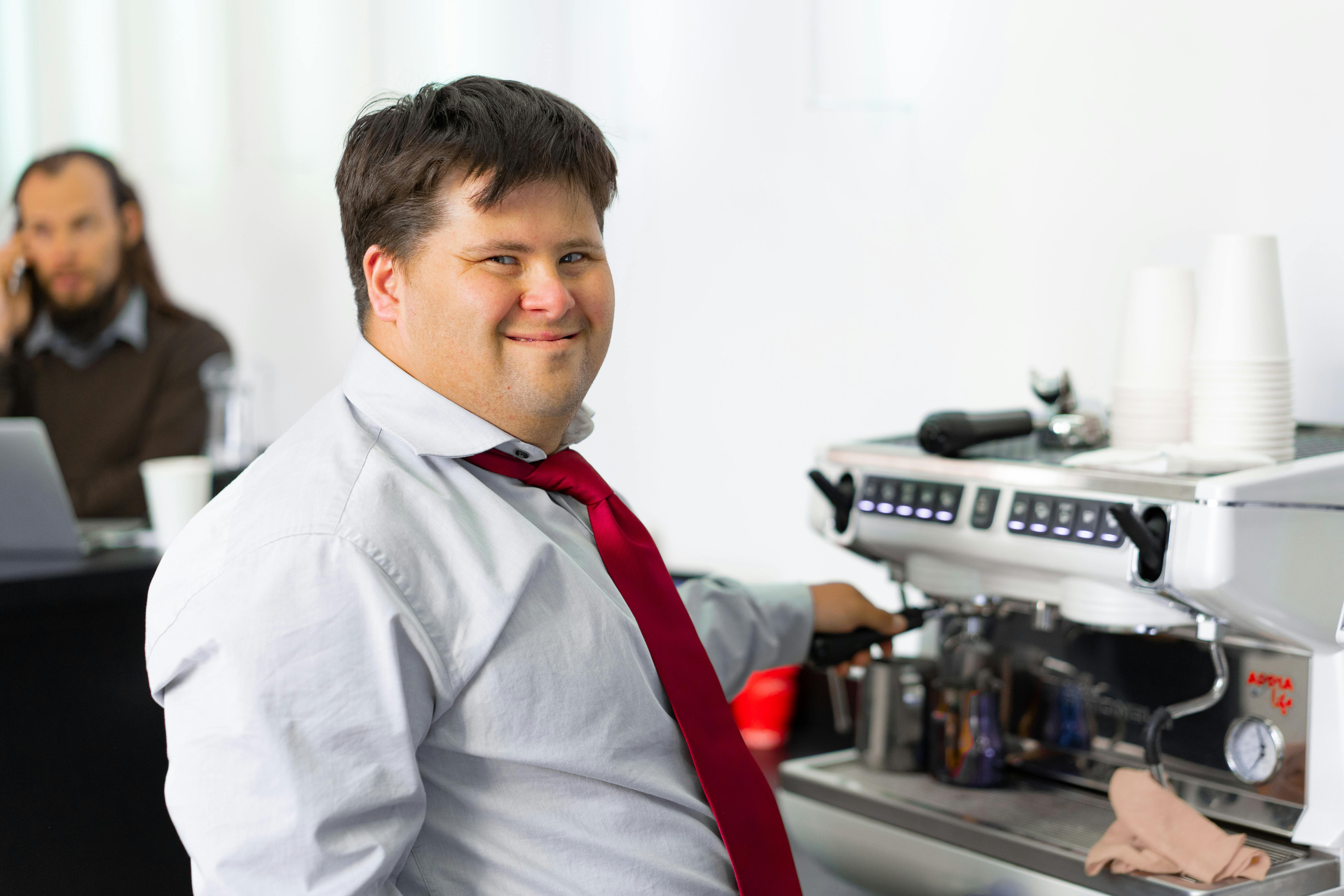 Un homme souriant alors qu'il se tient devant une machine à café | Source : Pexels