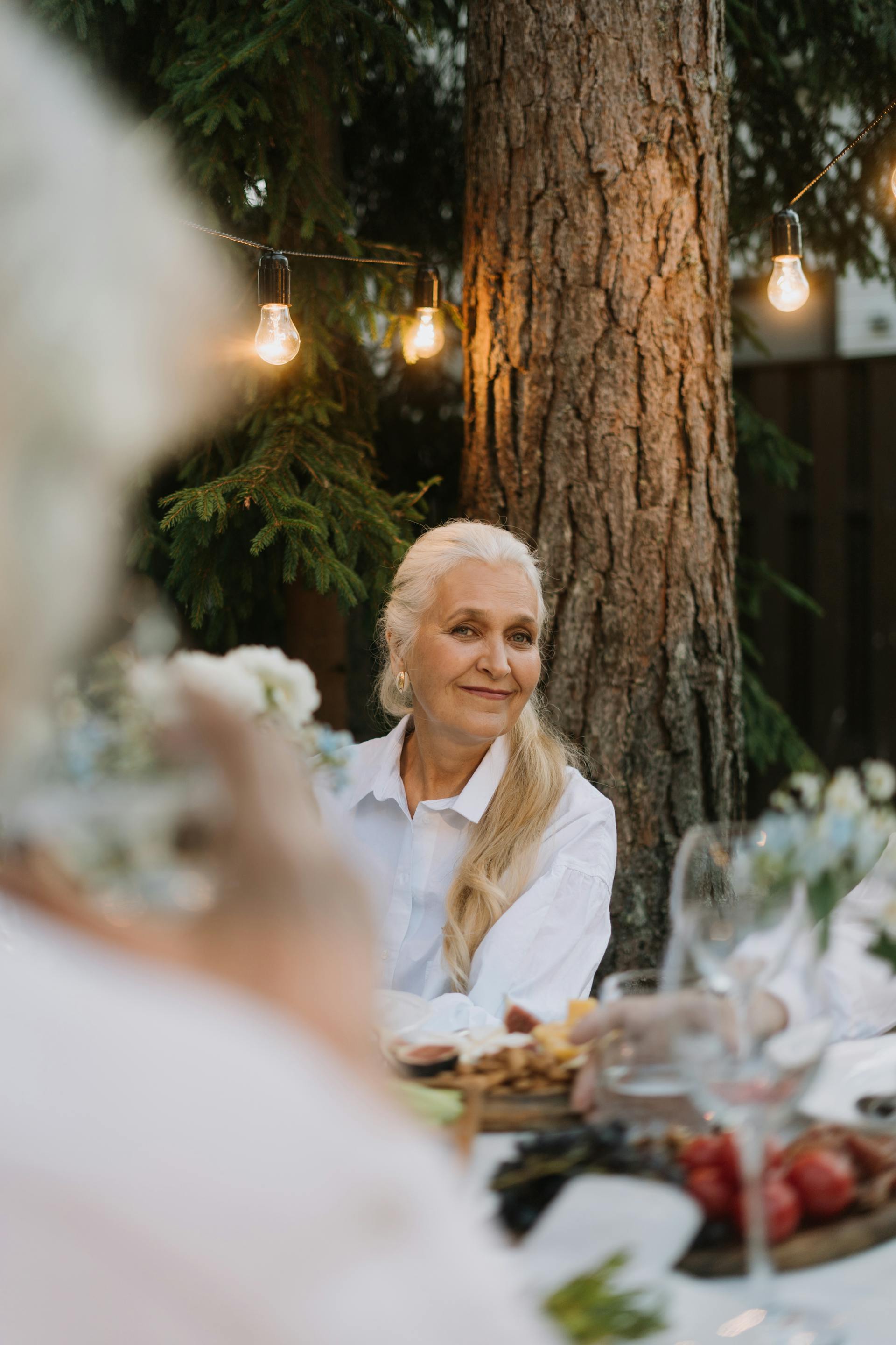 Une femme d'âge mûr aux longs cheveux blonds souriant lors d'une fête | Source : Pexels