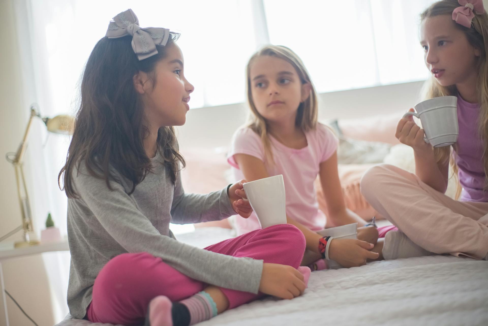 Trois filles tenant des tasses tout en discutant | Source : Pexels