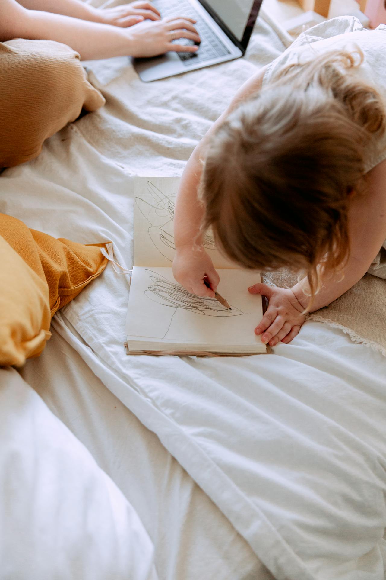 Femme travaillant sur son ordinateur portable pendant que sa petite fille gribouille sur un cahier | Source : Pexels