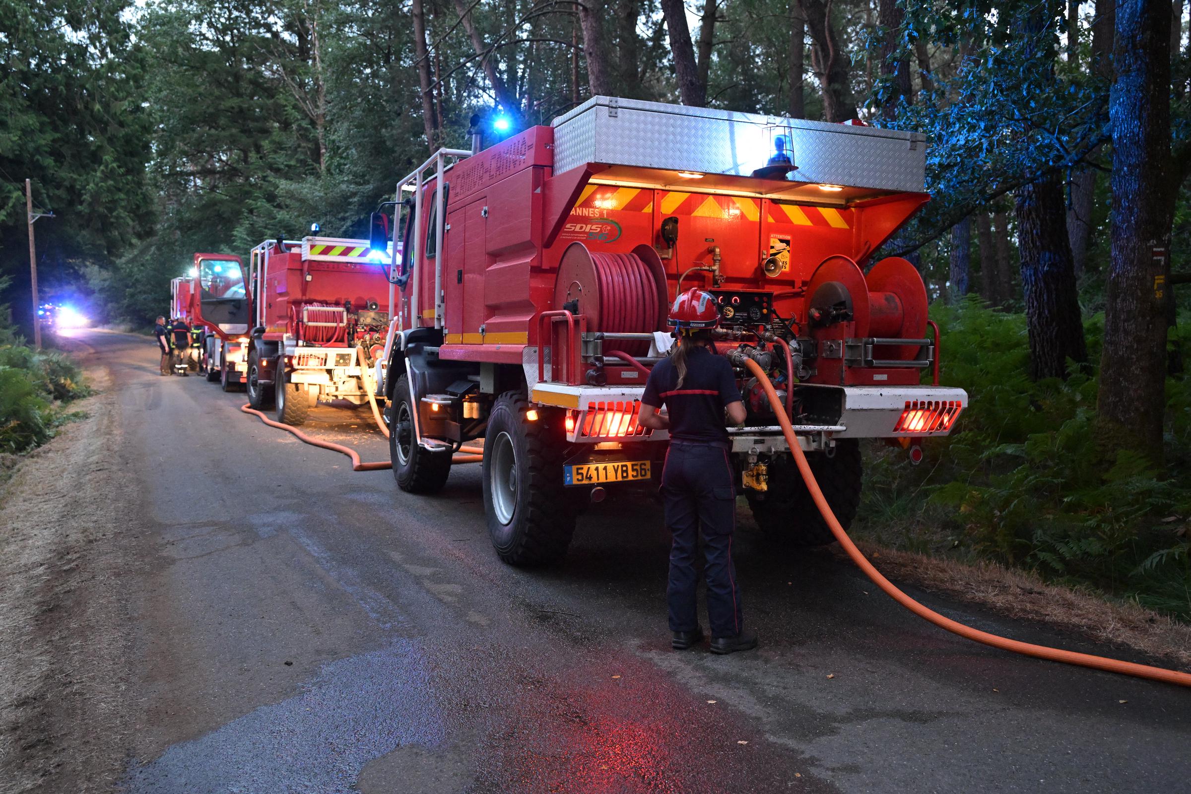 Un pompier se tient à côté d'un véhicule appartenant au SDIS 56 - les pompiers du Morbihan sont stationnés sur le bord d'une route près de la forêt de Brocéliande après qu'un incendie s'est déclaré, à Tréhorenteuc, dans l'ouest de la France, le 17 juillet 2025 I Source : Getty Images
