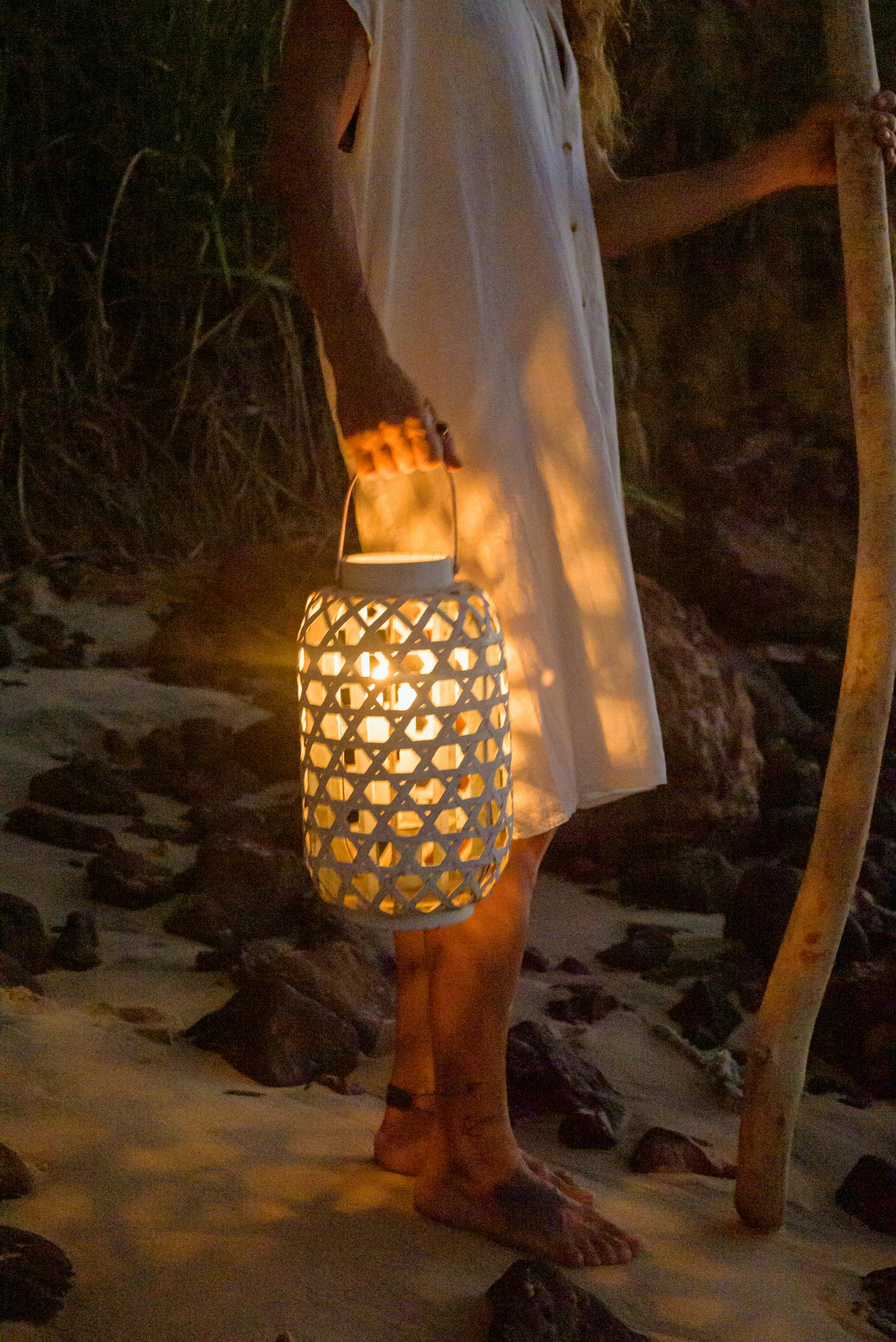 Une femme debout sur la plage tenant une lanterne | Source : Pexels