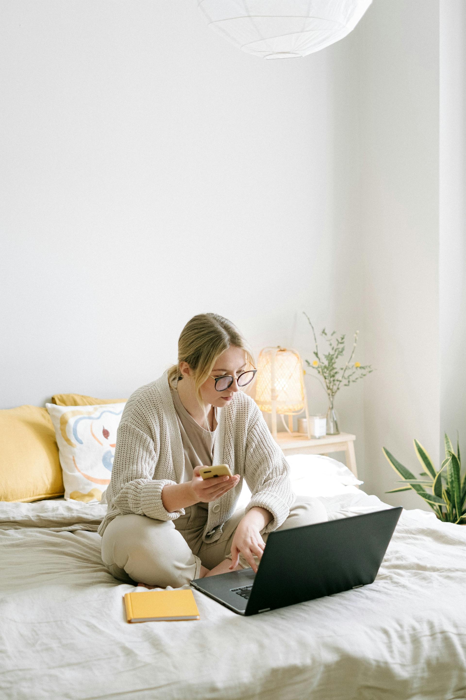 Une femme utilisant un ordinateur portable et tenant un téléphone | Source : Pexels