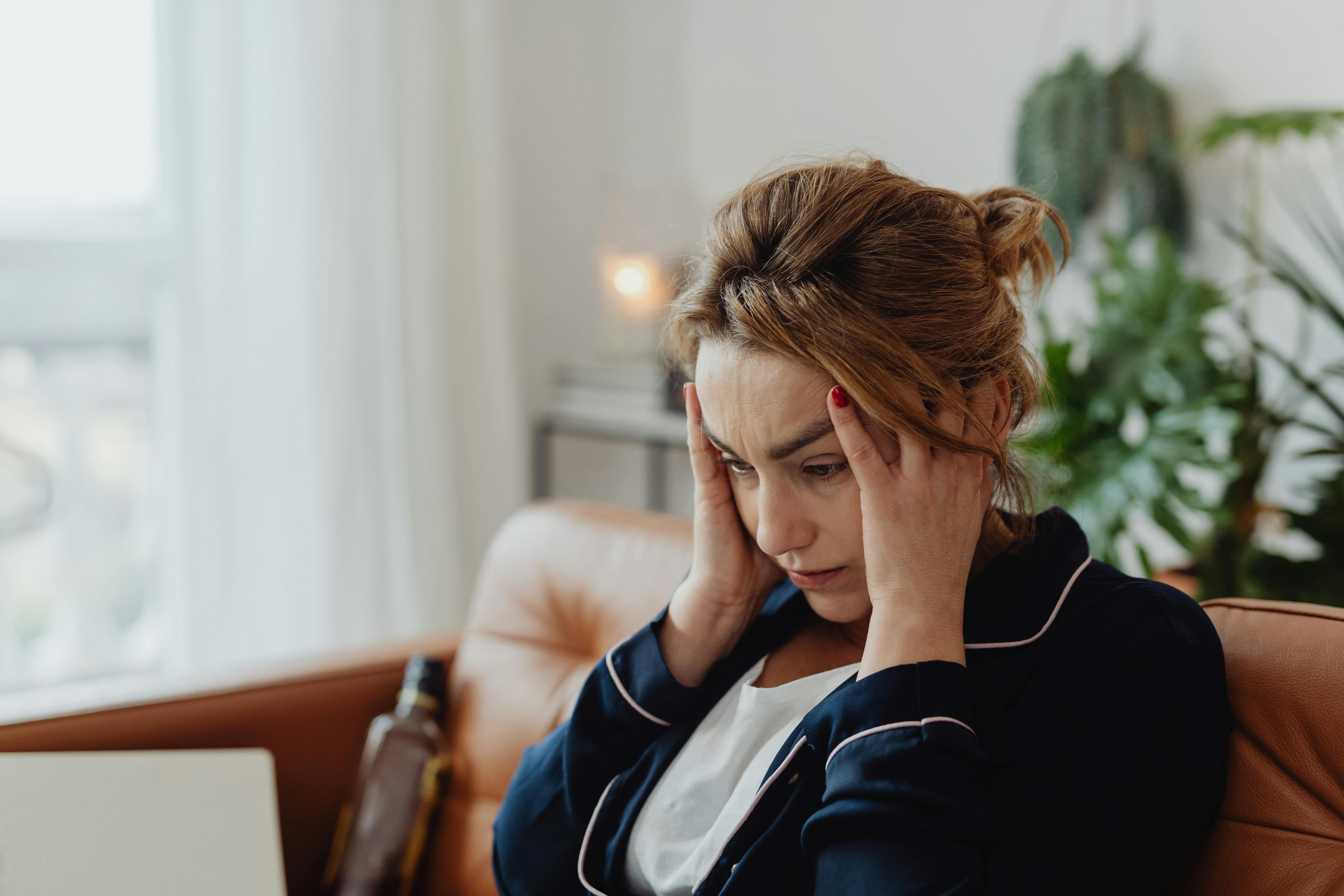 Une femme assise sur un canapé et se tenant la tête | Source : Pexels
