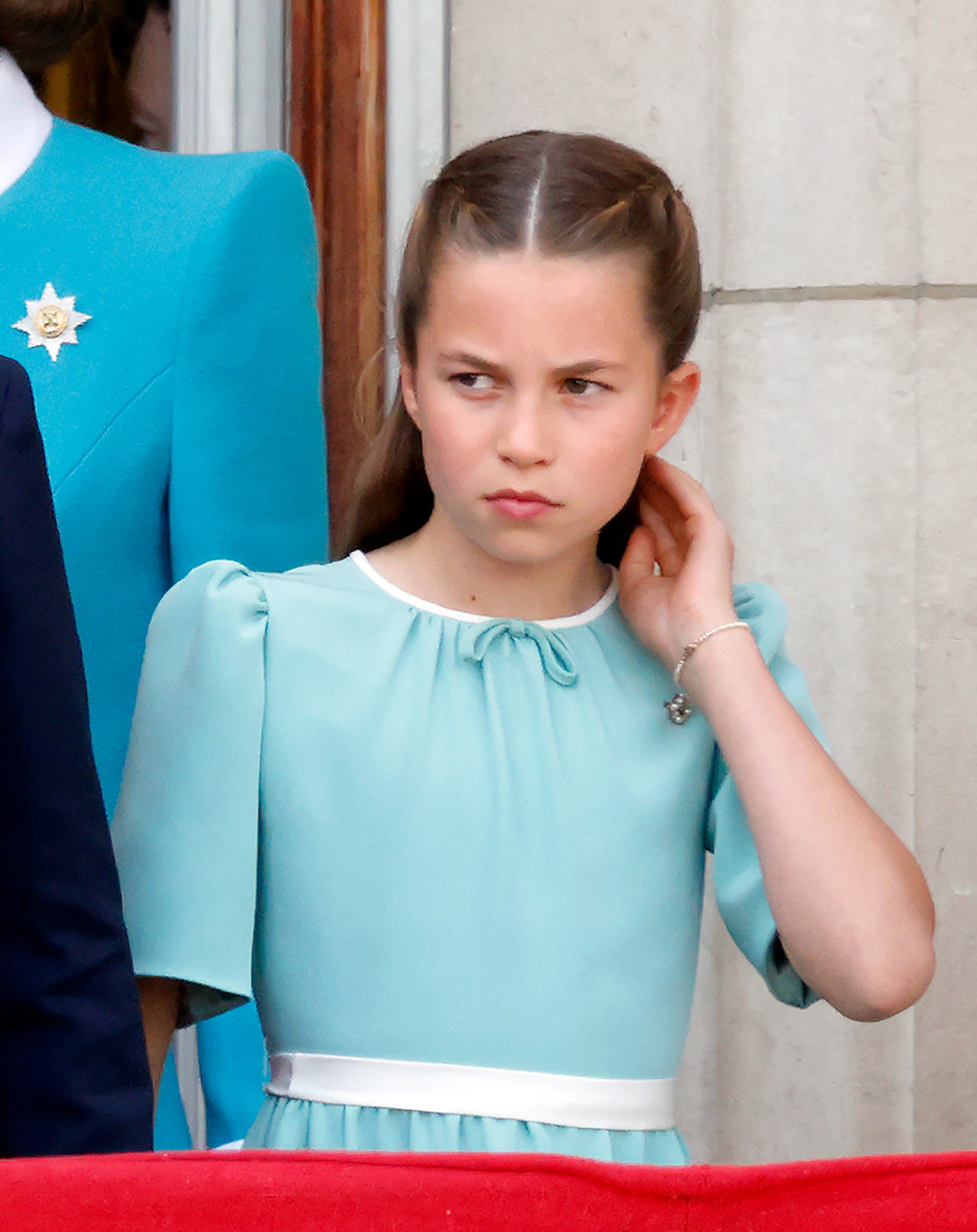 La princesse Charlotte de Galles, dans sa magnifique robe blanche et aigue-marine, sa superbe coiffure et son bracelet, se touche les cheveux et regarde un défilé aérien de la RAF depuis le balcon du palais de Buckingham lors du Trooping The Colour 2025 à Londres, en Angleterre, le 14 juin 2025.