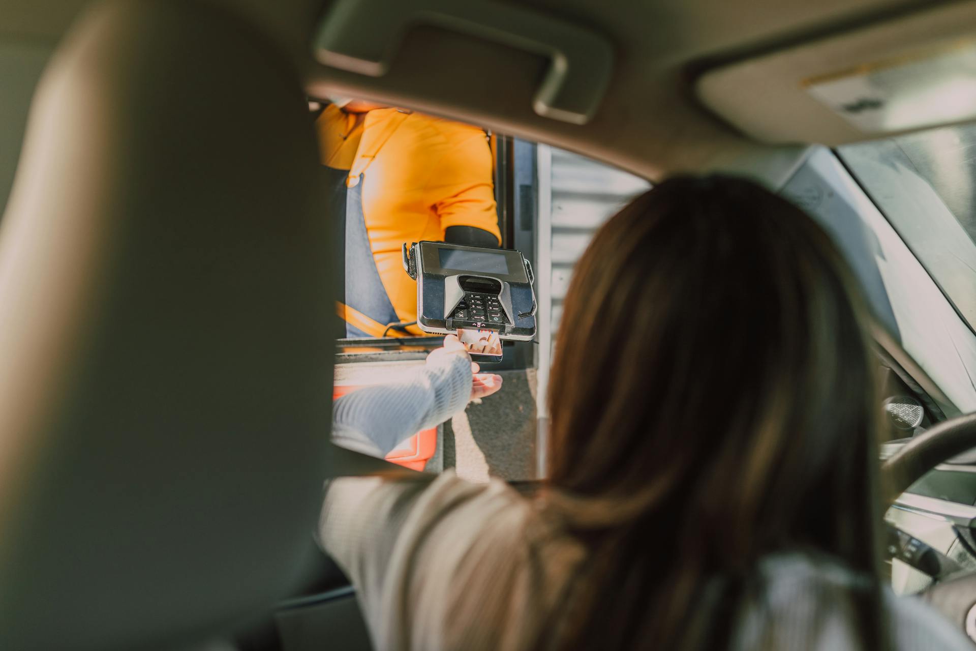 Une femme assise dans sa voiture et effectuant un paiement au drive-in | Source : Pexels