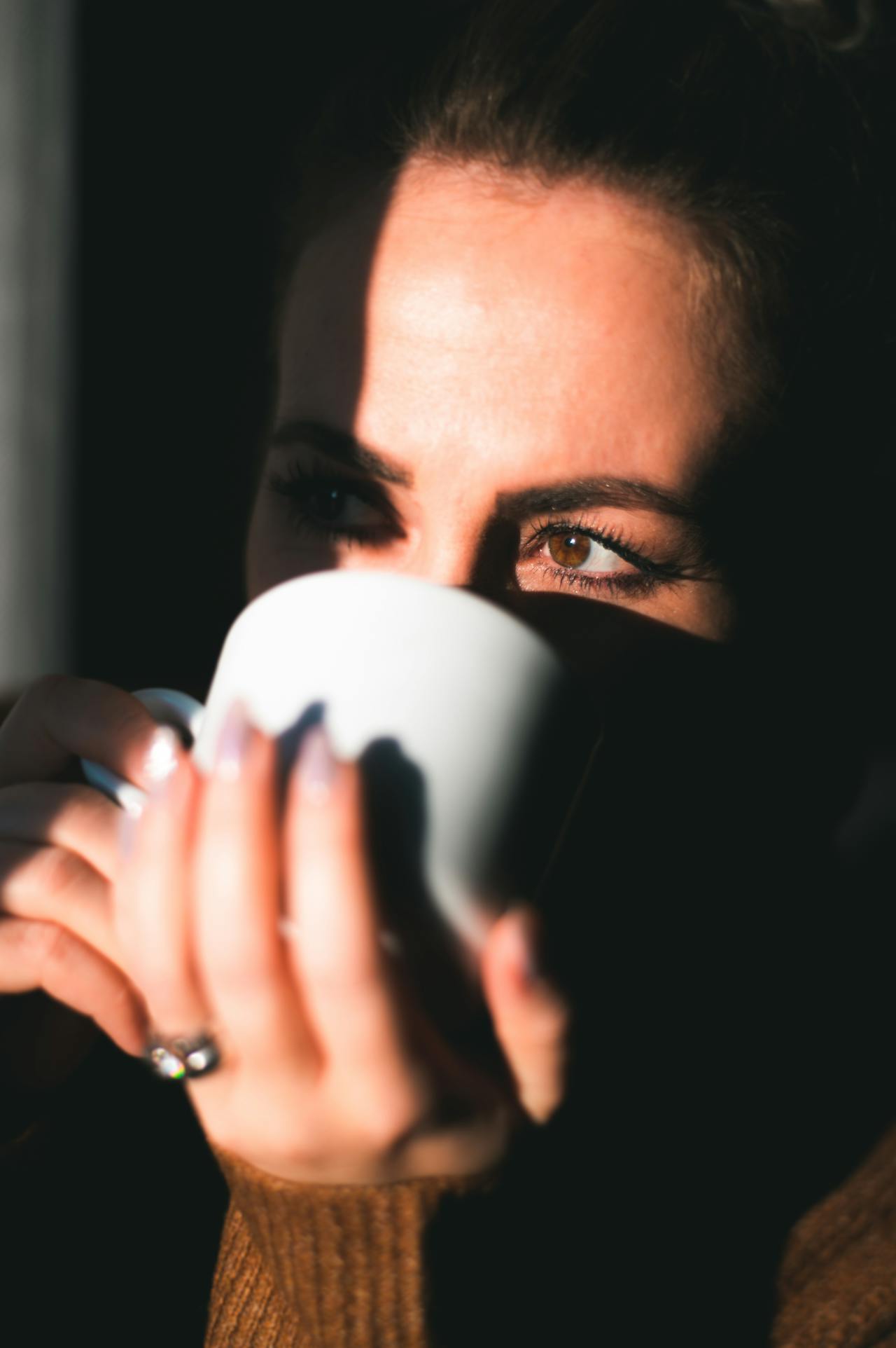 Une femme buvant une boisson dans une tasse en céramique blanche | Source : Pexels