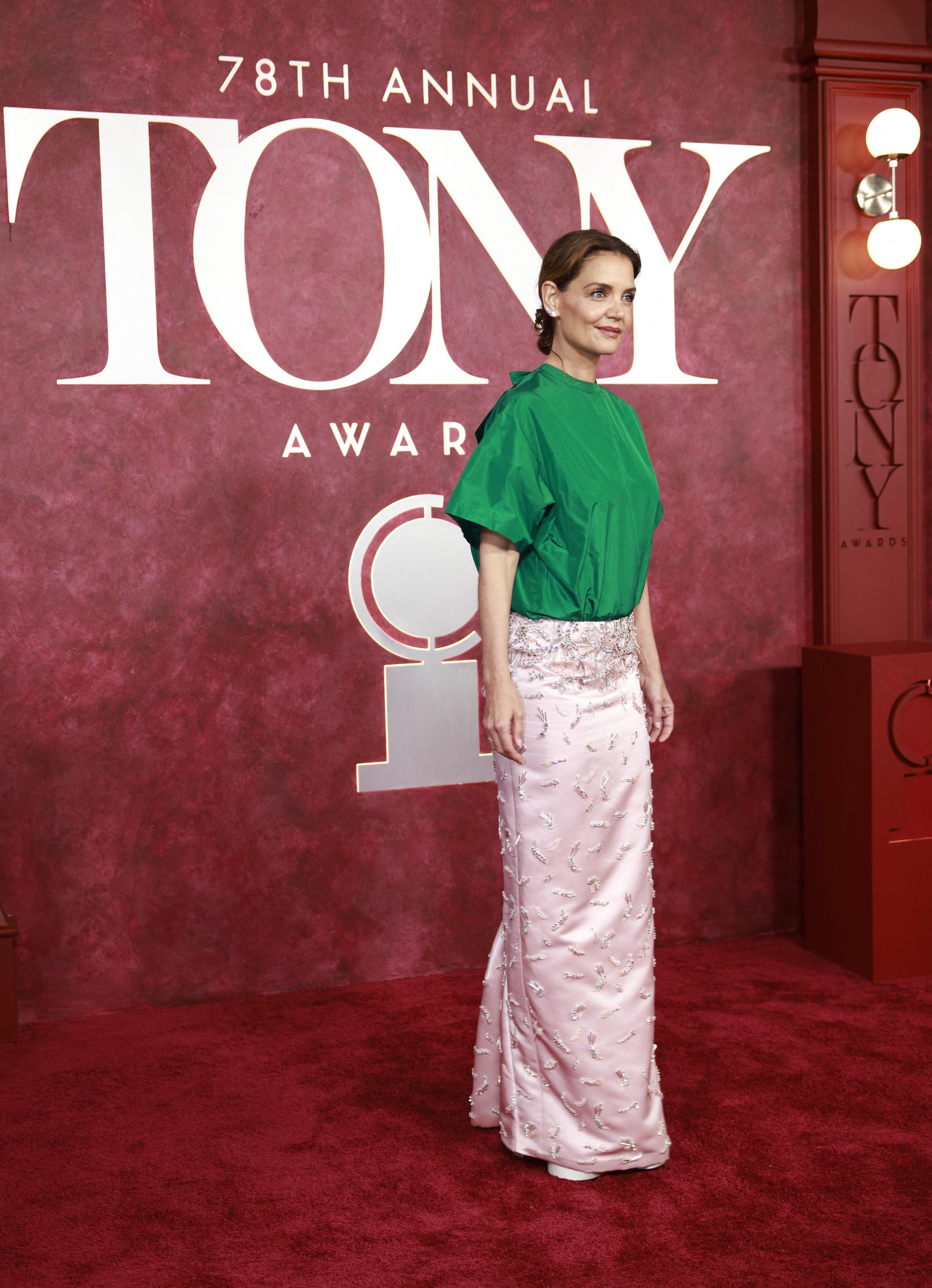 Avec un pied légèrement en avant et une posture posée, Katie Holmes domine le tapis rouge dans son ensemble vert et rose. La photo capture à la fois l'élégance et l'audace - à l'image des réactions que son look a suscitées sur les réseaux sociaux.