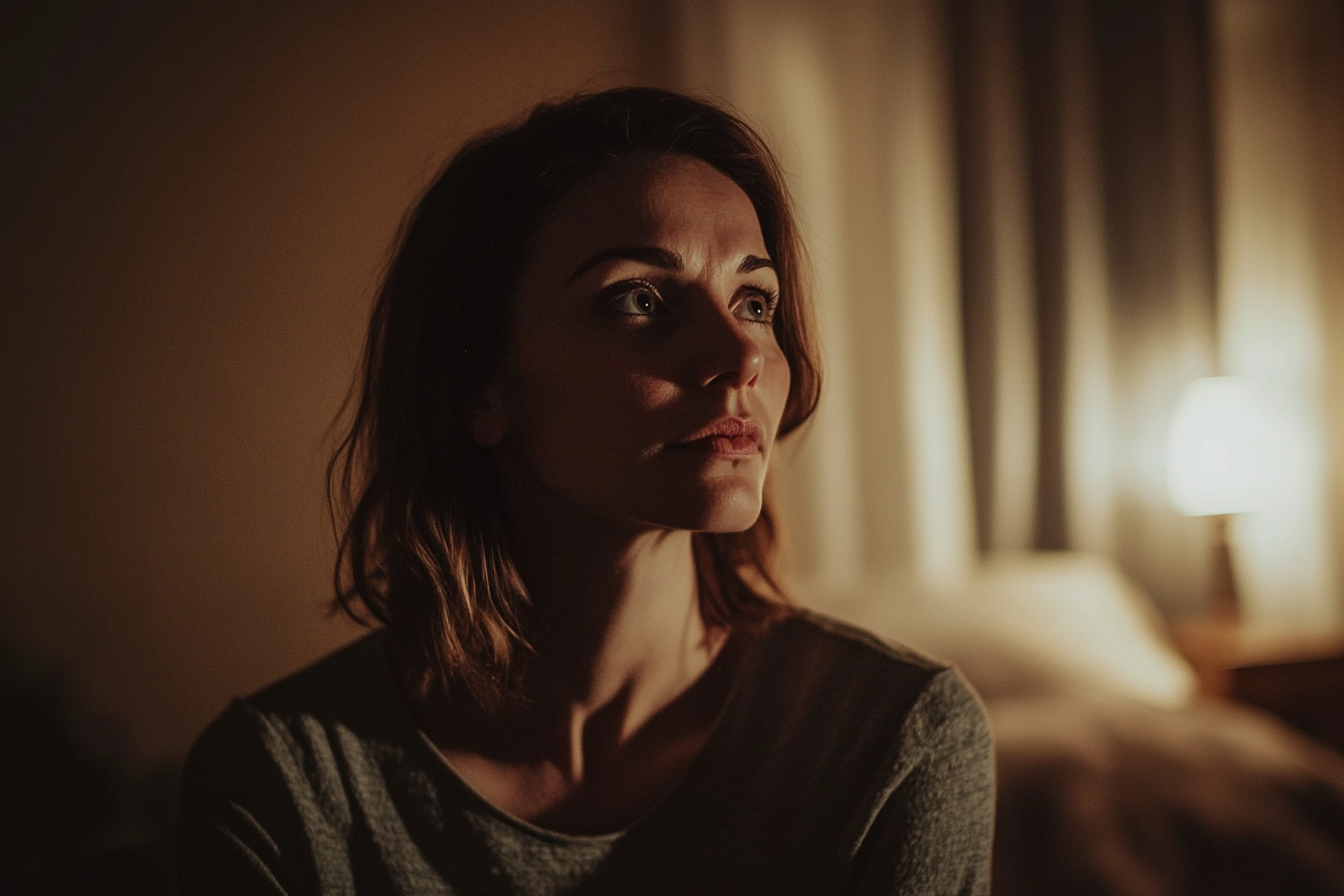 Une femme émotive se tenant dans une chambre à coucher la nuit | Source : Midjourney
