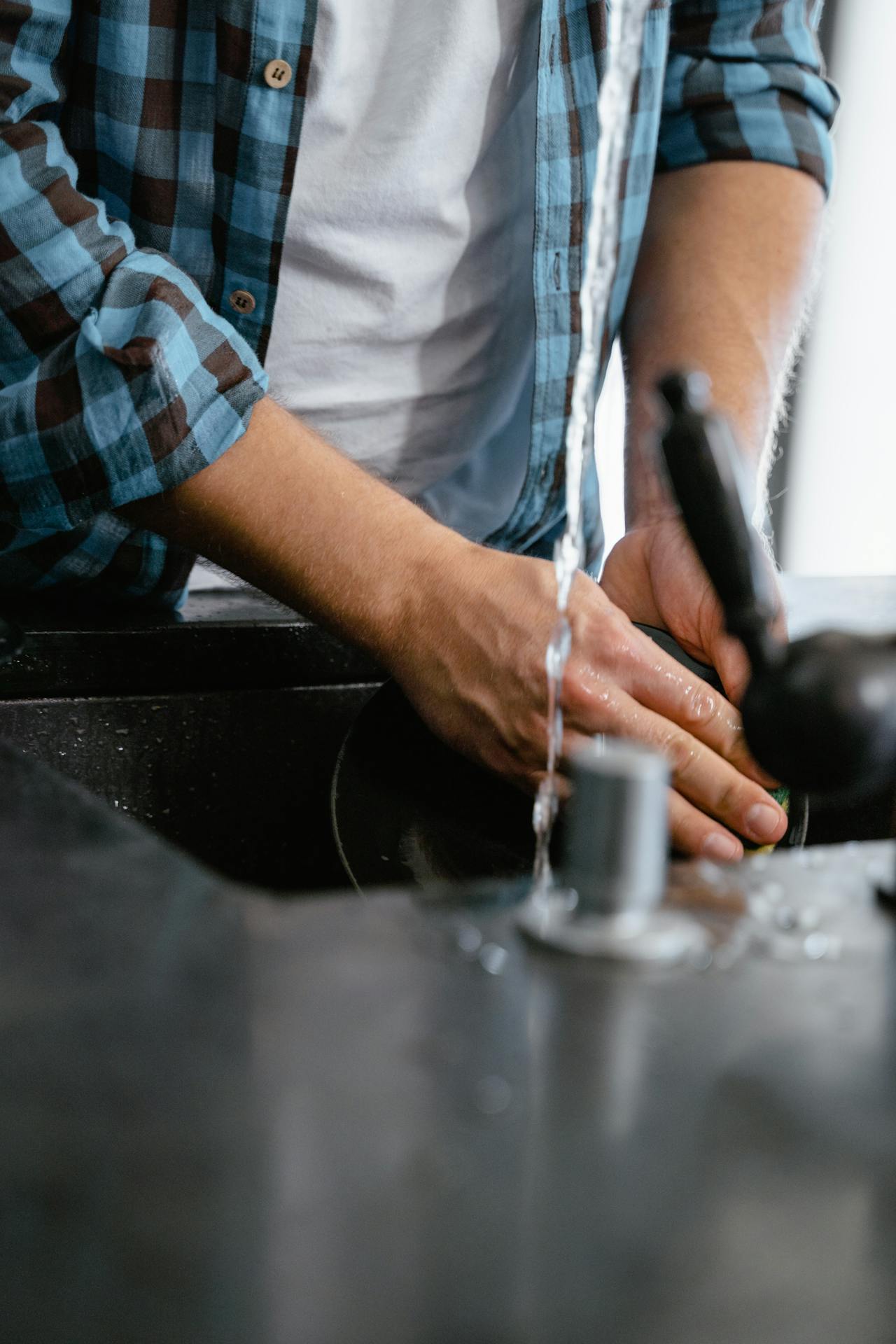 Photo recadrée d'un homme en train de laver une assiette | Source : Pexels