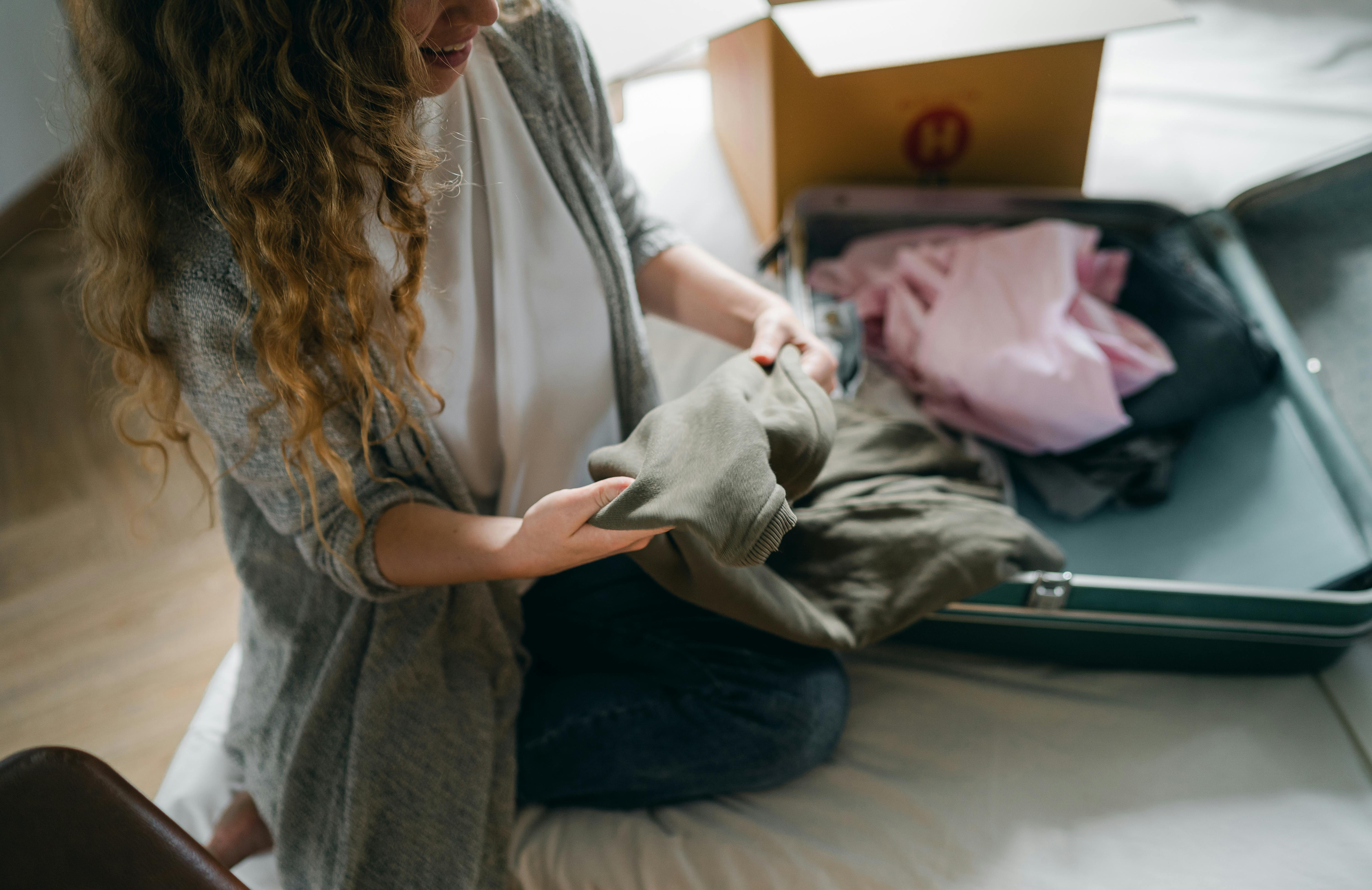 Une femme rangeant ses vêtements dans une valise | Source : Pexels