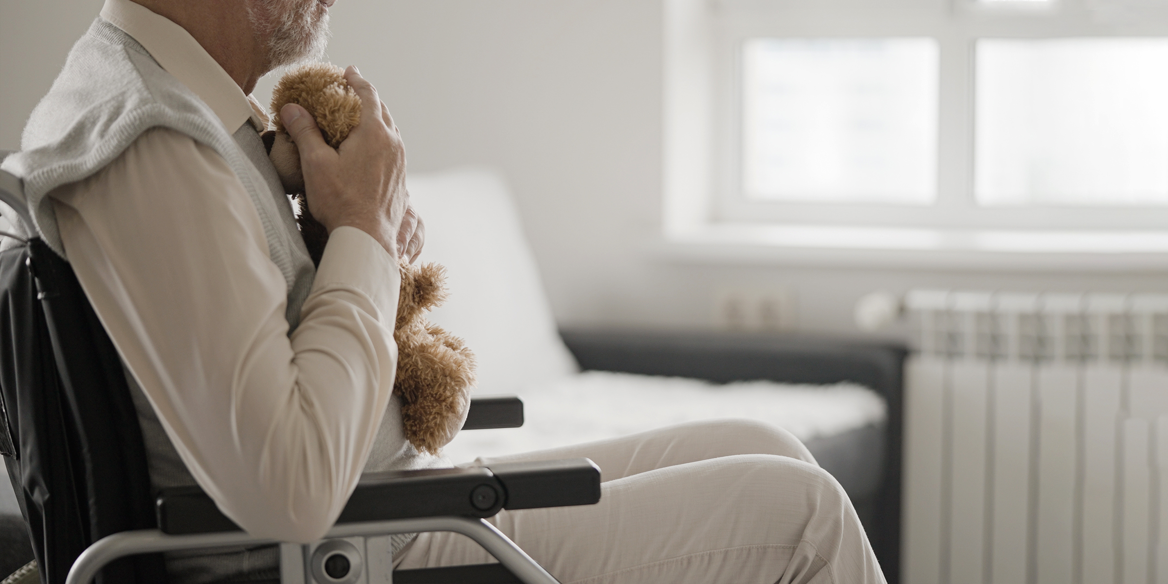 Un homme âgé assis dans un fauteuil roulant avec un ours en peluche | Source : Shutterstock