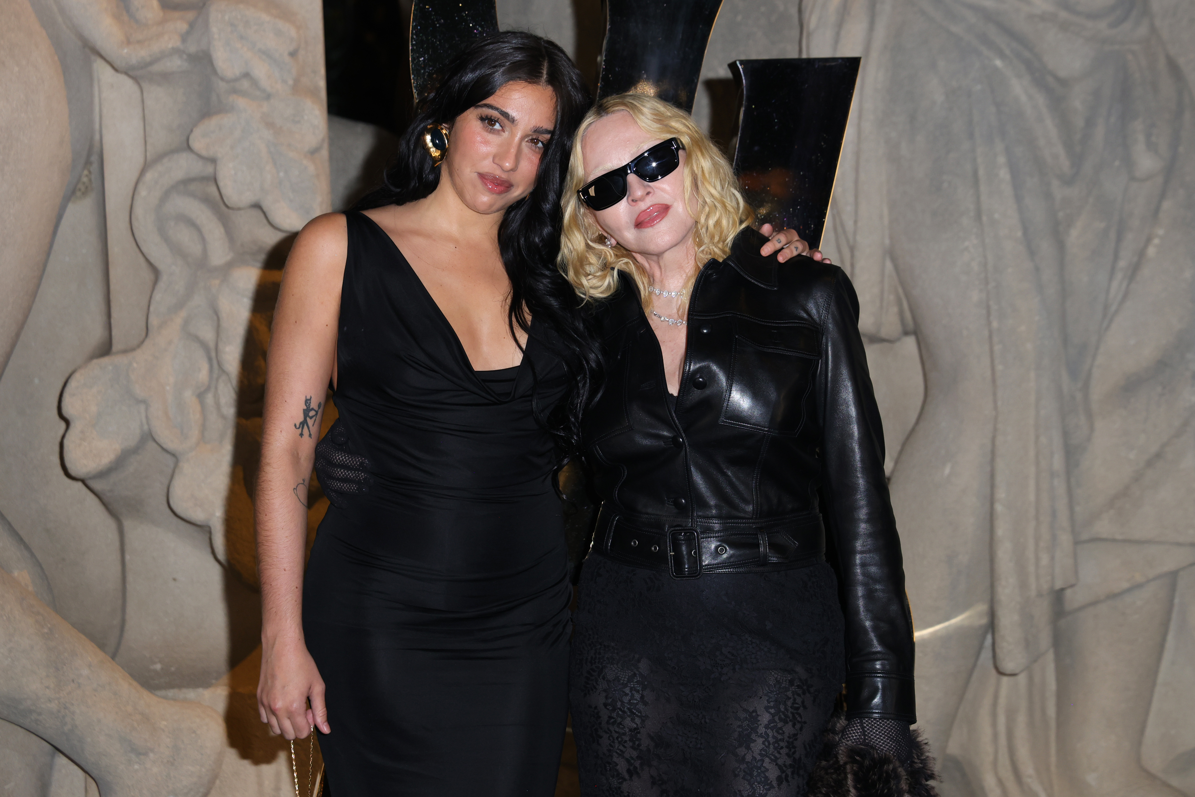 Lourdes Leon et Madonna assistent au défilé Saint Laurent printemps/été 2026 lors de la Fashion Week de Paris, qui se tient à la Fontaine du Trocadéro en France. Madonna porte un haut boutonné en cuir noir ceinturé, une jupe transparente et des collants noirs, accessoirisés de chaînes incrustées de diamants. Leon a opté pour une robe midi noire à dos nu. Elle complète son look avec des collants noirs transparents.