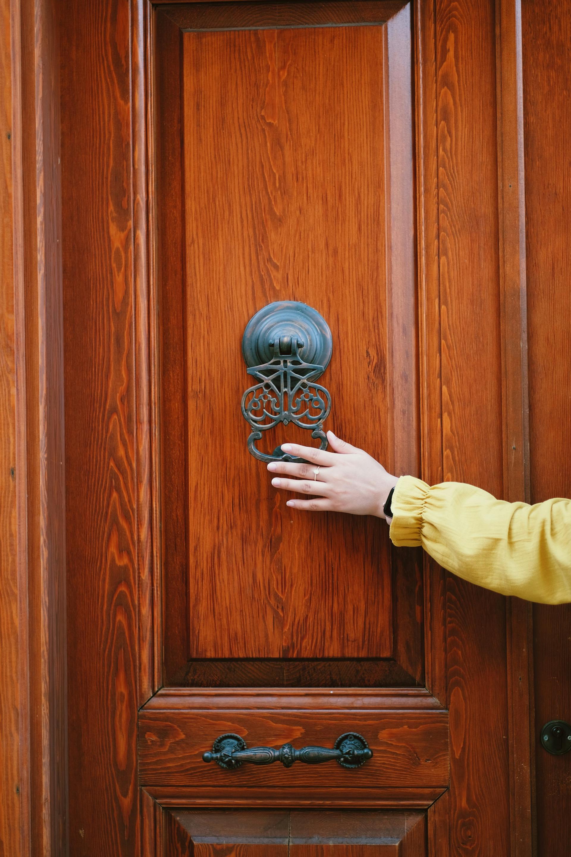 Une personne tenant un heurtoir de porte | Source : Pexels