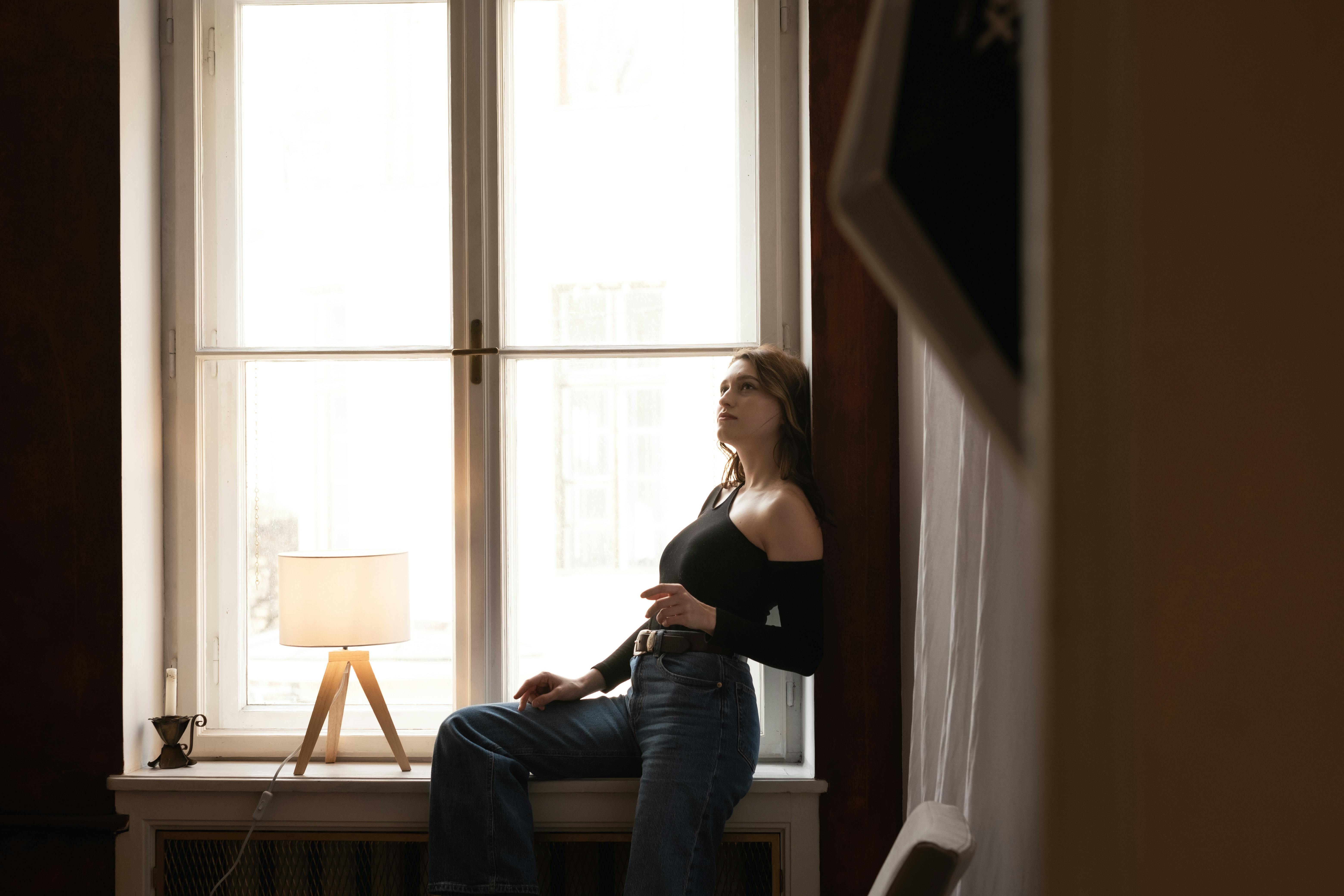 Une femme assise sur le bord d'une fenêtre | Source : Pexels