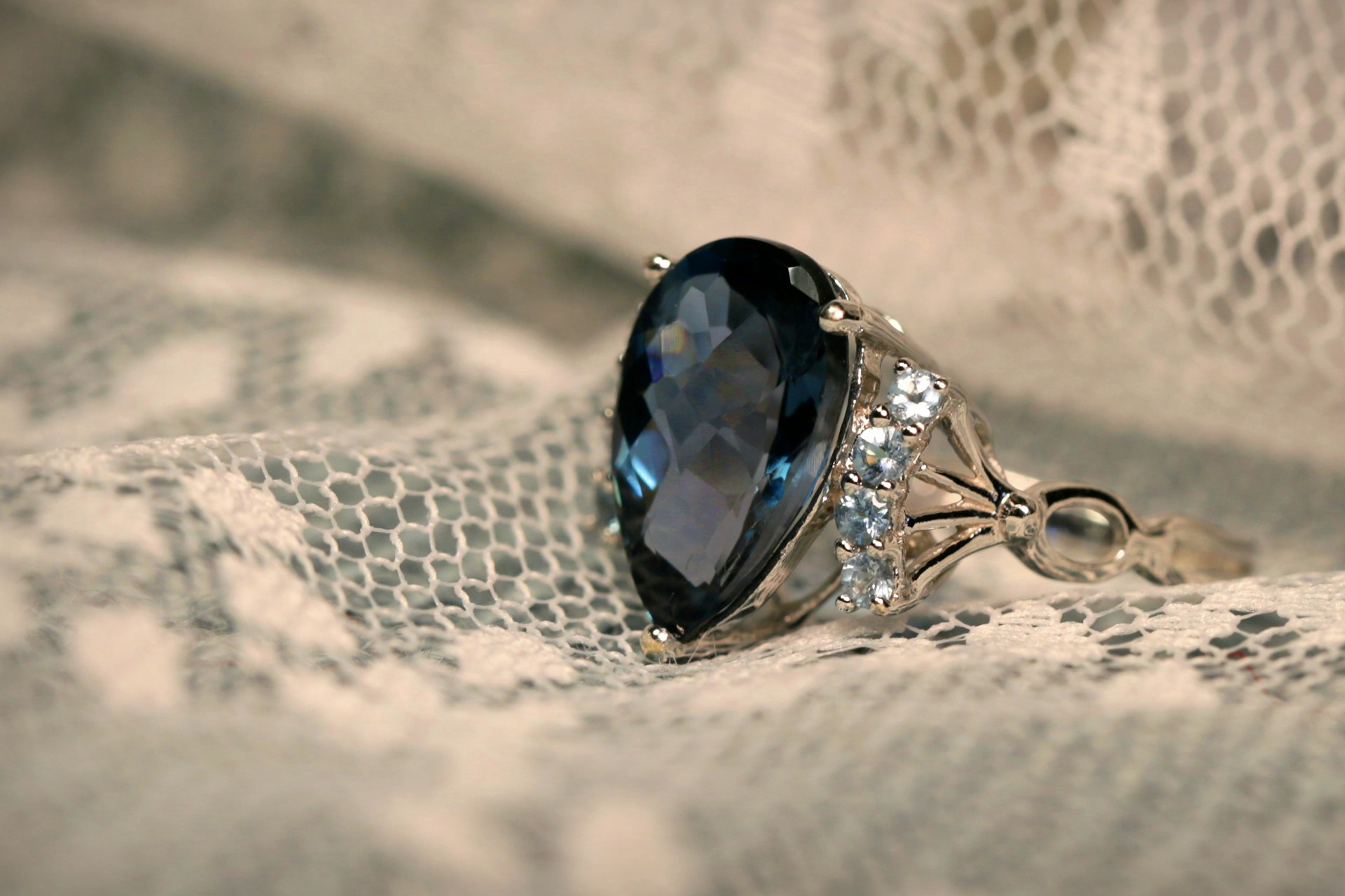 Une bague sertie de pierres sur un tissu en dentelle blanche | Source : Unsplash