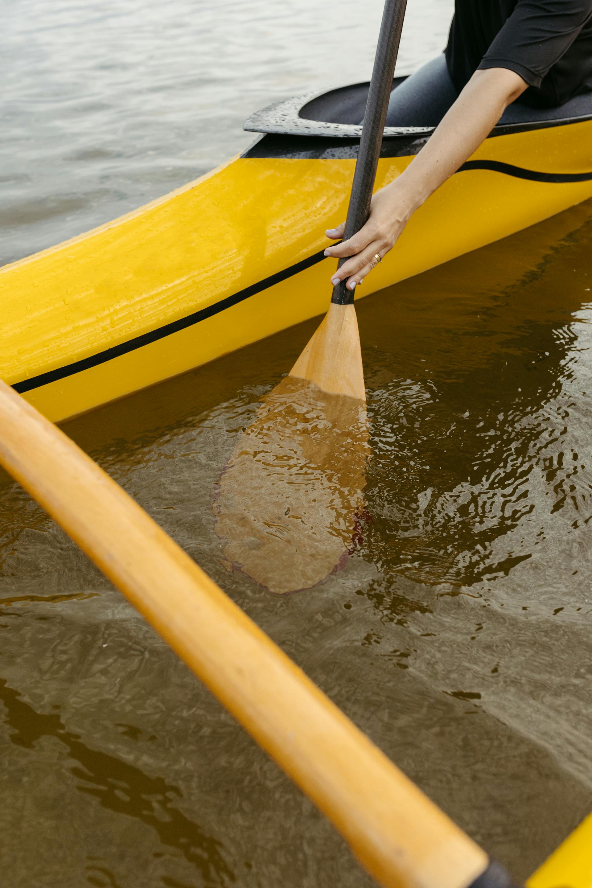 Gros plan d'une personne pagayant sur un canoë jaune | Source : Pexels