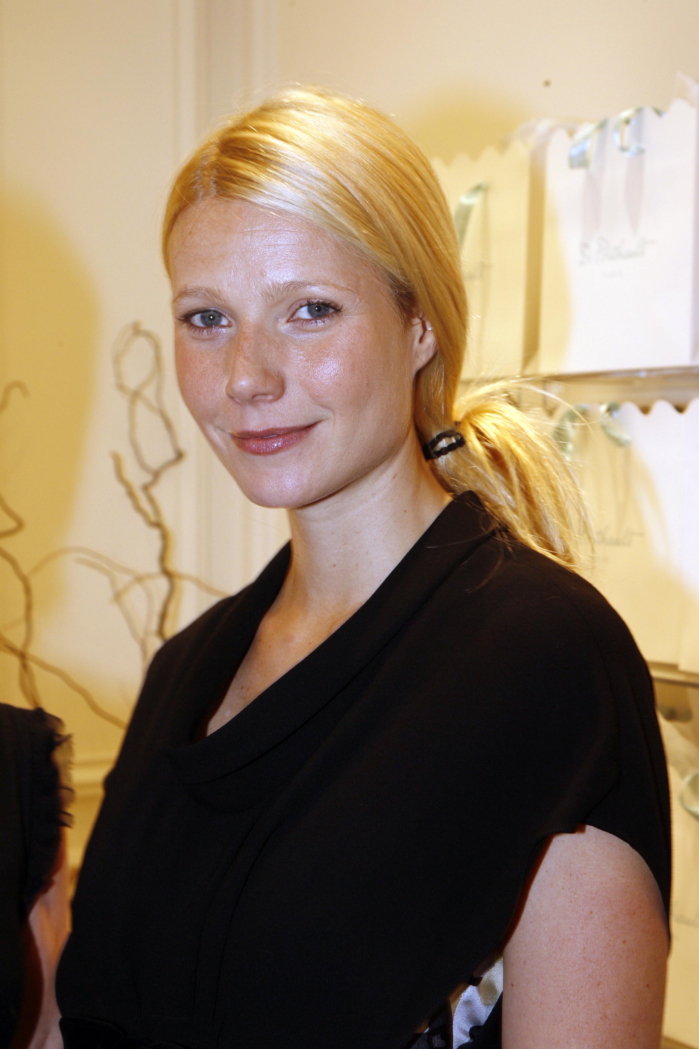 Gwyneth Paltrow assiste à une soirée de la Fashion Week de Paris en France, le 5 octobre 2006. Elle porte une robe noire structurée avec un décolleté drapé moderne, tandis que ses cheveux blonds sont rassemblés en une queue de cheval basse. Un éclat subtil sur son teint et une touche de gloss donnent à son look une finition raffinée mais discrète.