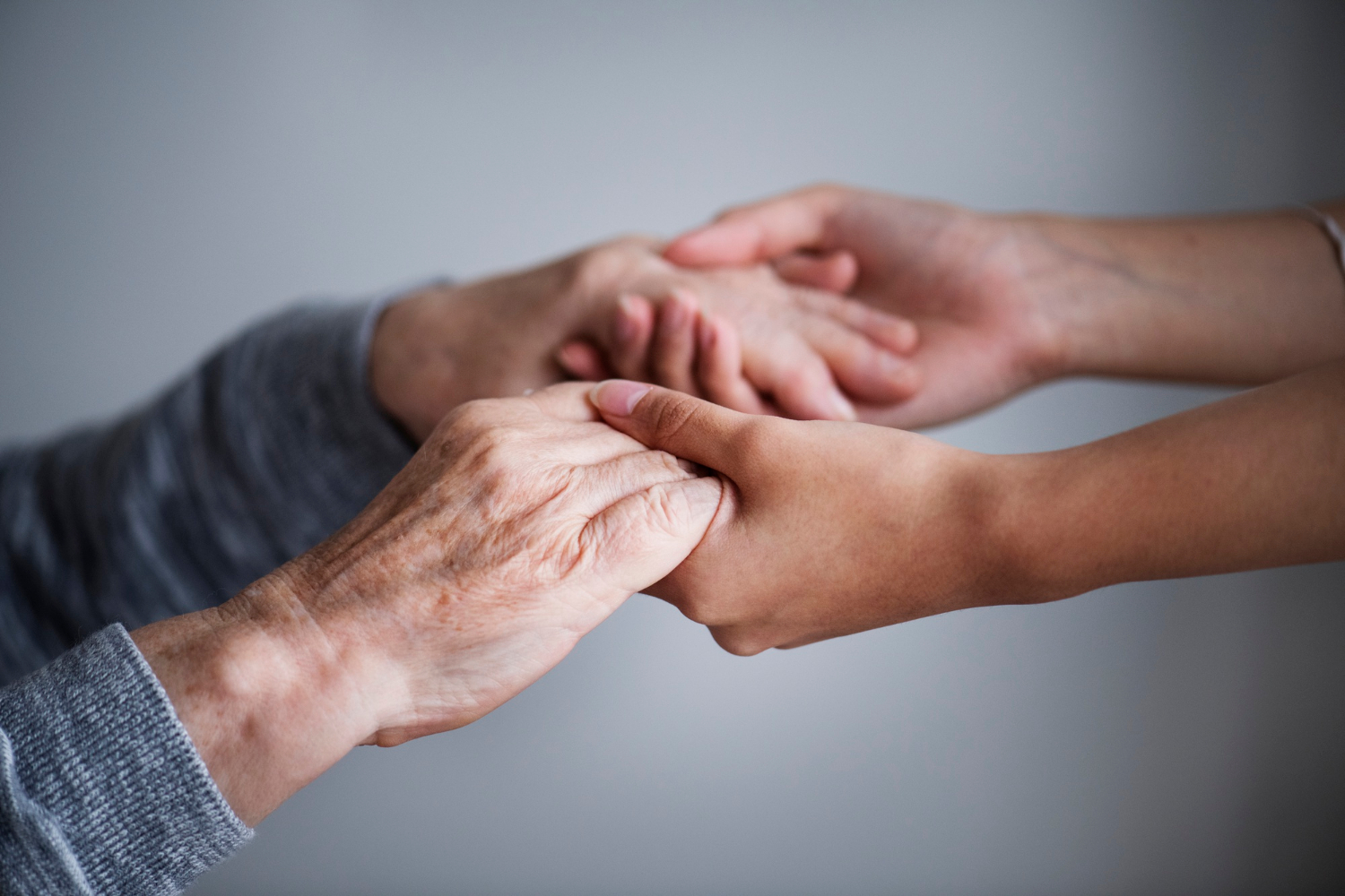 Une jeune femme tenant les mains d'une femme plus âgée lui offrant soutien et assurance | Source : Freepik