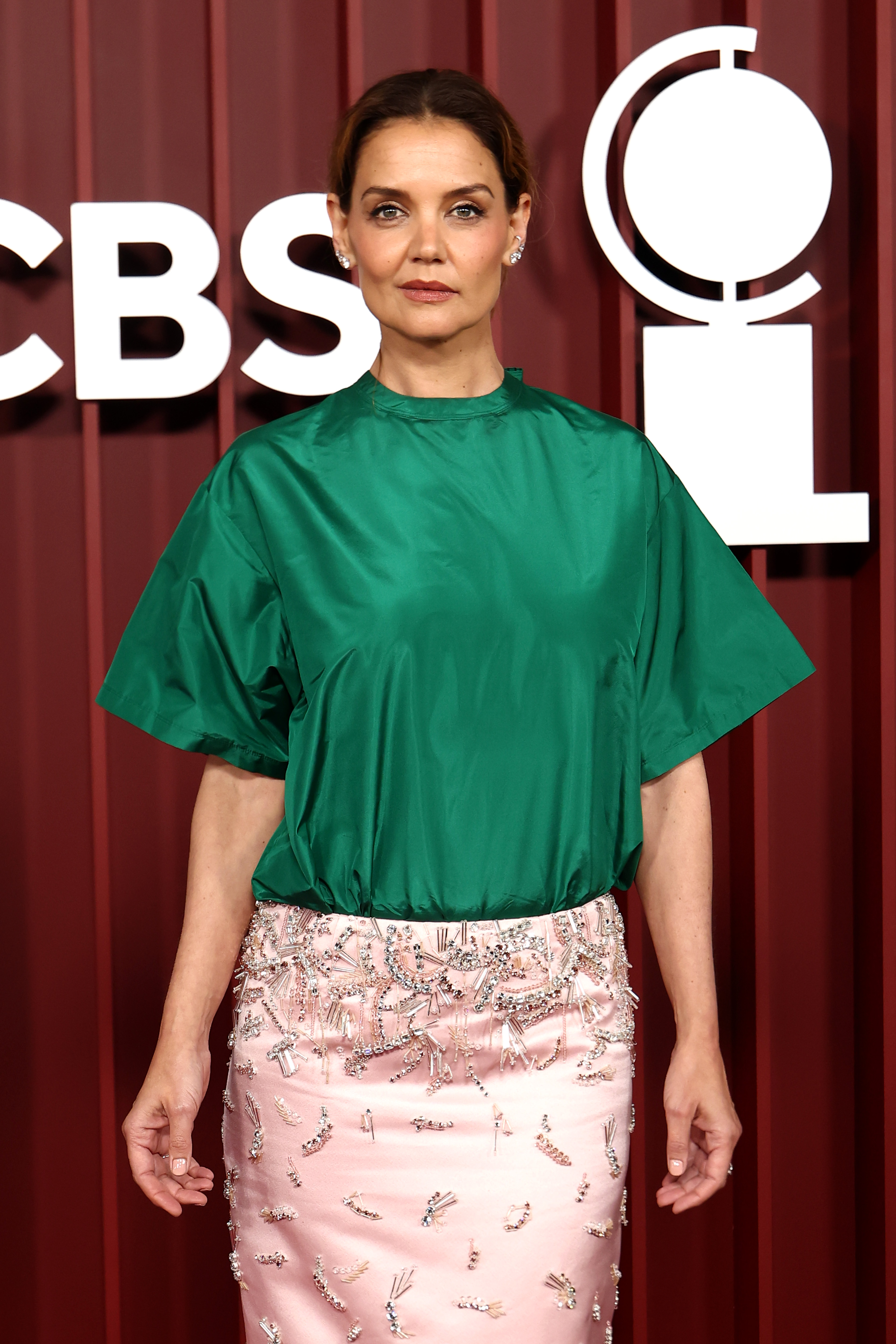 Katie Holmes pose au premier plan lors de la 78e cérémonie des Tony Awards dans un haut structuré en satin vert et une jupe rose pâle ornée de broderies en cristal. Son expression posée ajoute de l'élégance à cette association de couleurs audacieuse au Radio City Music Hall.