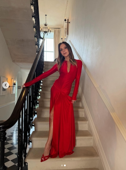 Victoria Beckham pose sur un escalier dans une robe rouge longue avec une fente jusqu'à la cuisse et des talons assortis dans une publication pour la Saint-Valentin datée du 14 février 2026. | Source : Instagram/victoriabeckham