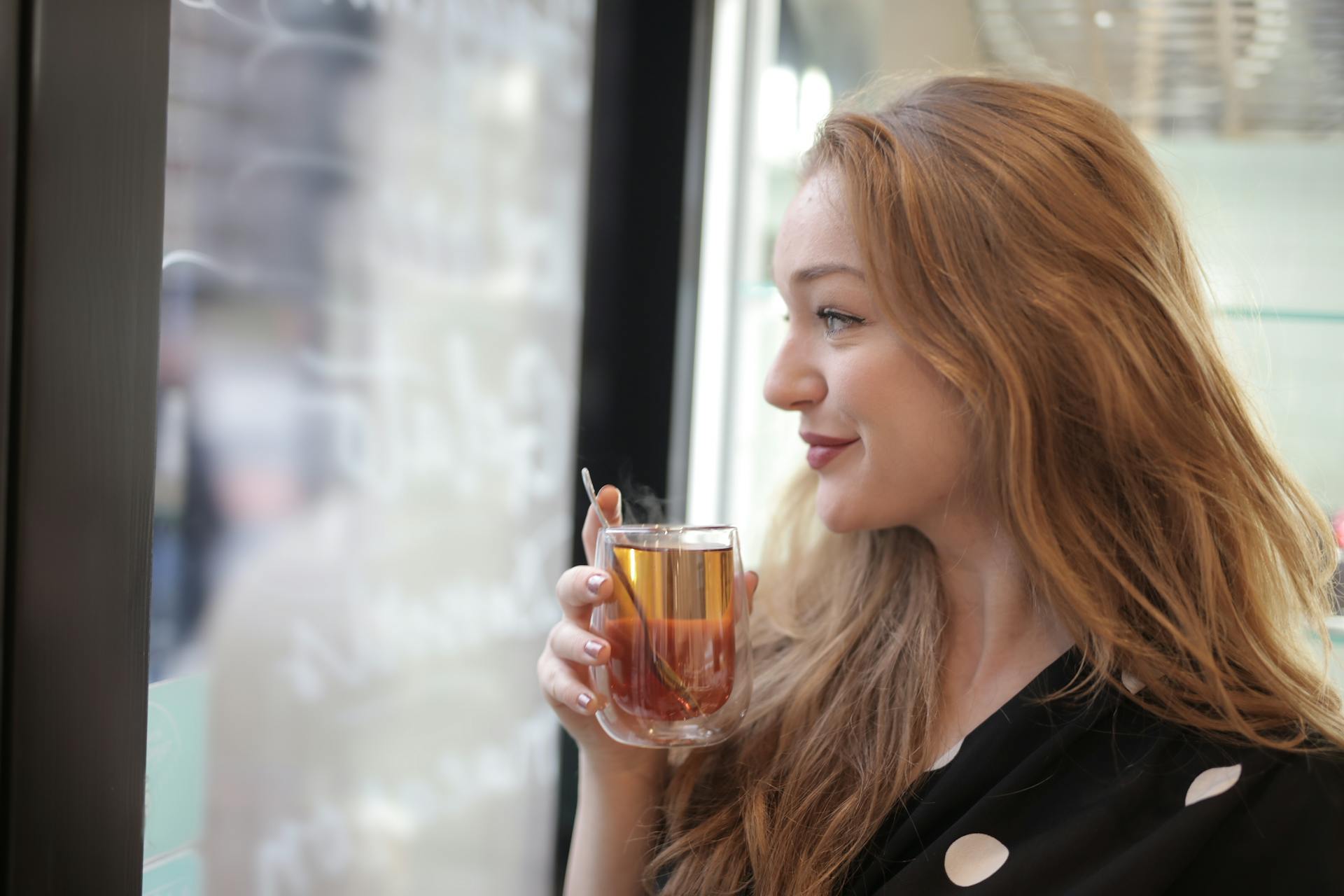 Une femme sourit triomphalement en tenant un verre dans ses mains | Source : Pexels