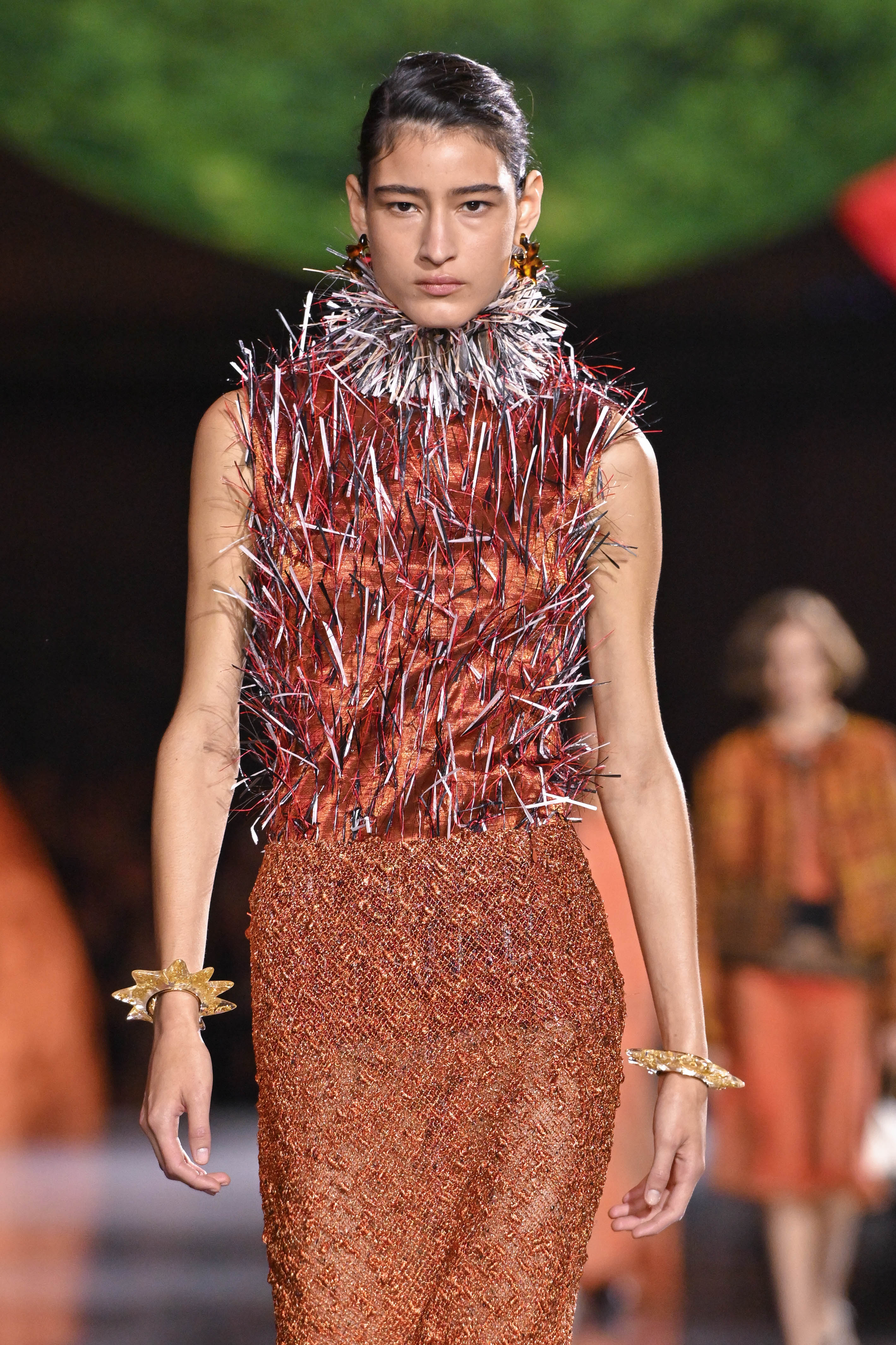 Une mannequin défile lors du défilé Chanel Prêt-à-porter Printemps/Été 2026 à la Fashion Week de Paris, en France. Elle porte une robe marron avec une jupe classique, tandis que le haut est revisité avec des détails saisissants en forme de pointes.