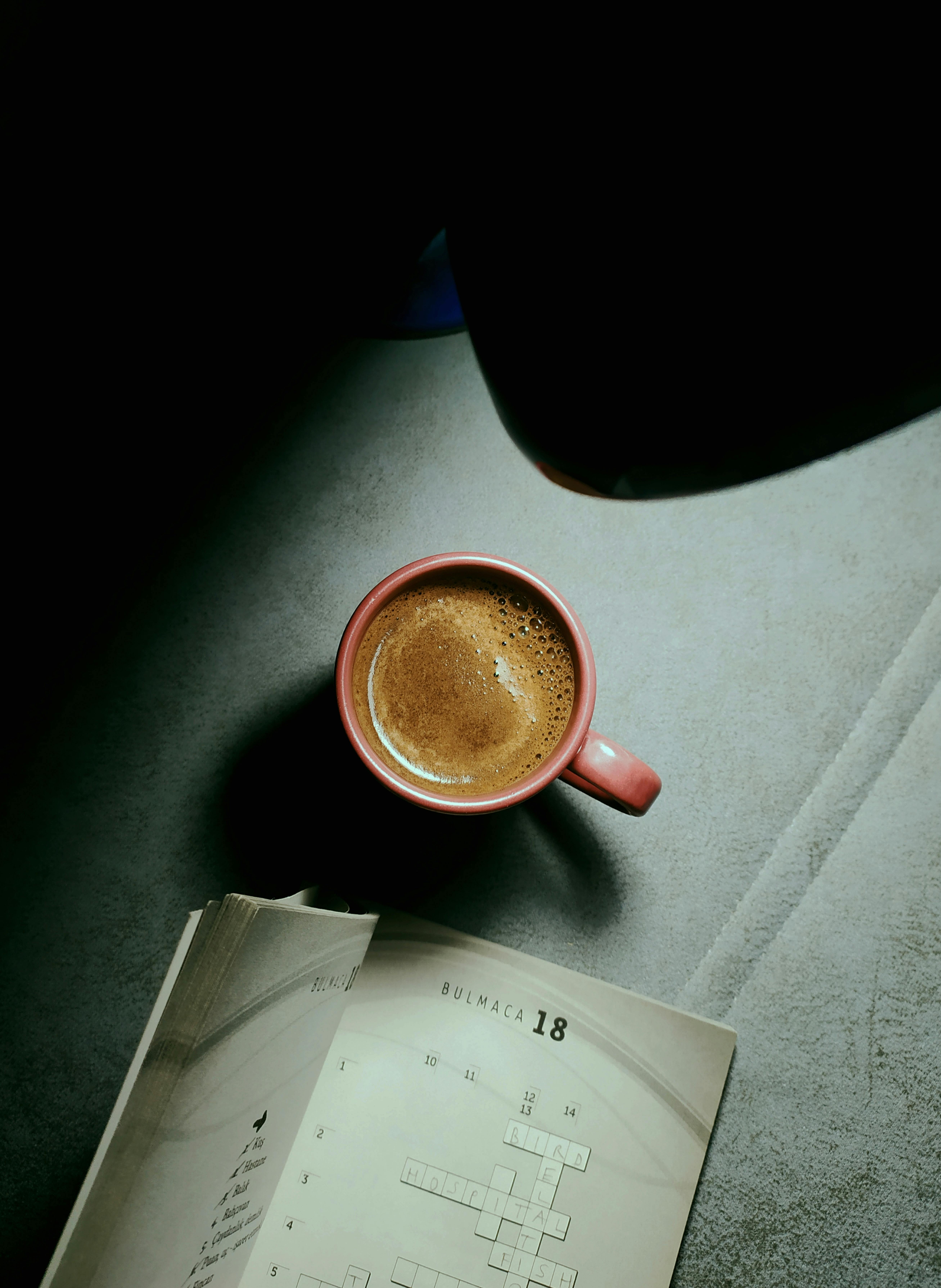 Un livre de mots croisés et une tasse de café | Source : Pexels