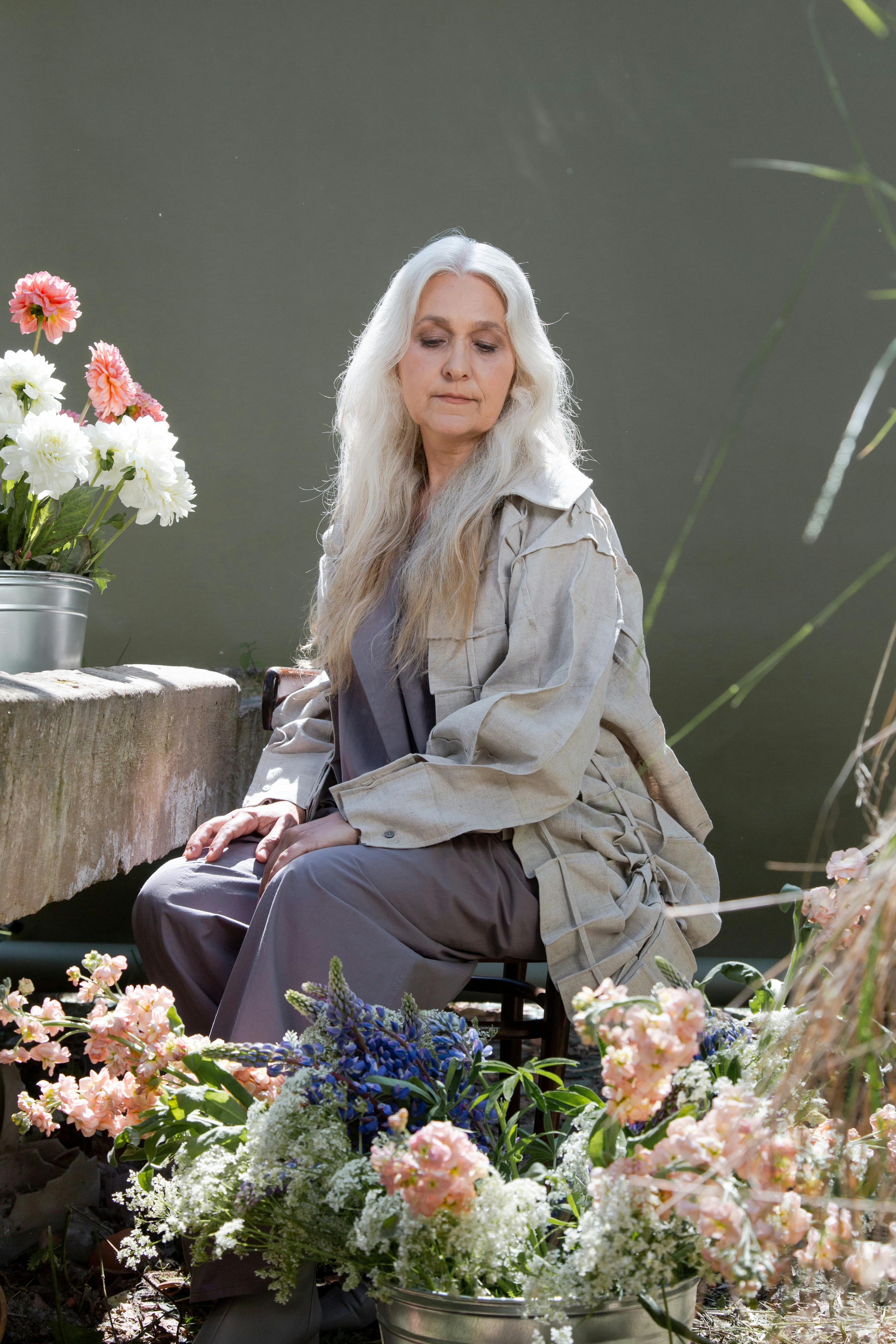Une femme âgée assise avec des fleurs | Source : Pexels