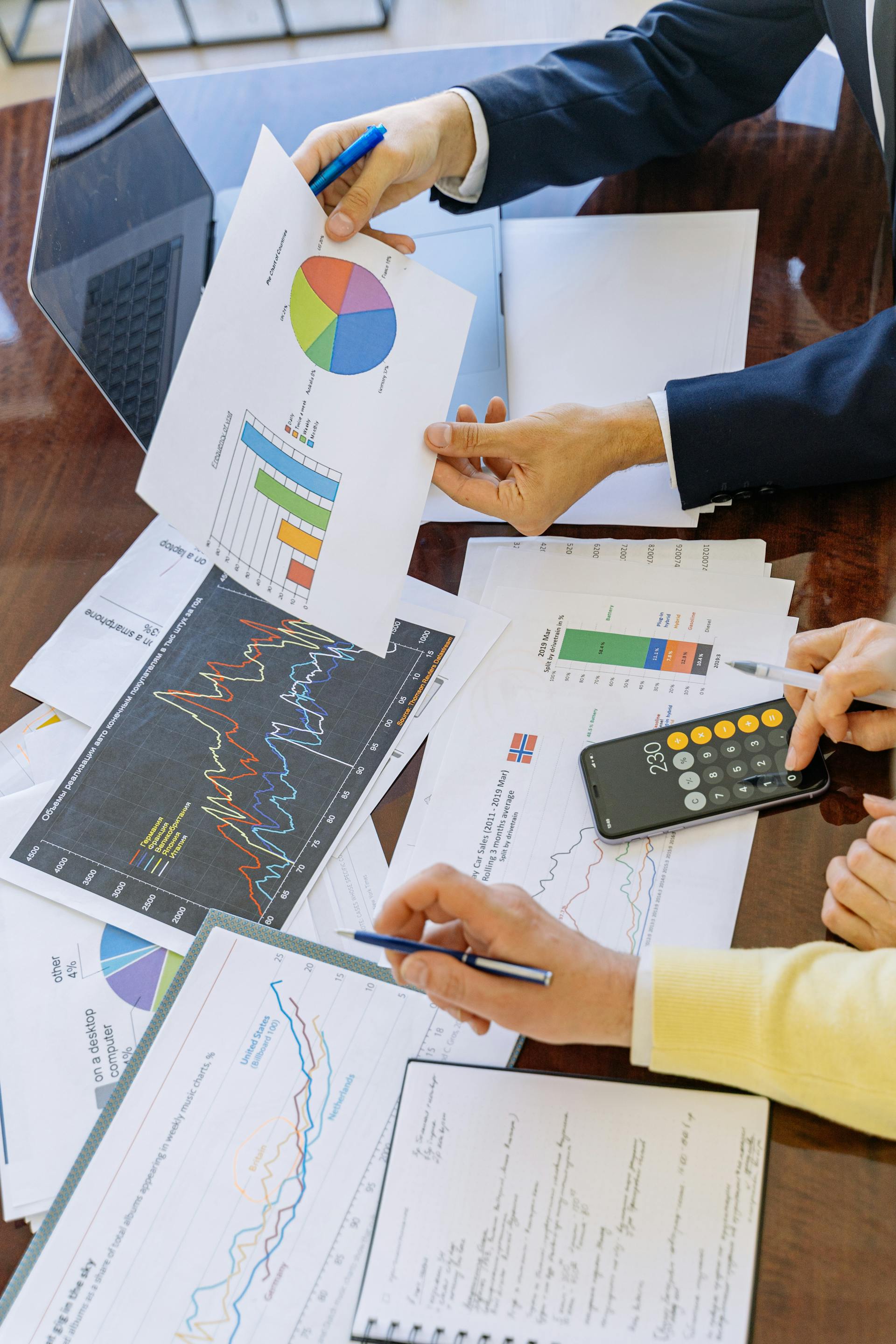 Gros plan de deux personnes analysant des graphiques et des camemberts dans un bureau | Source : Pexels